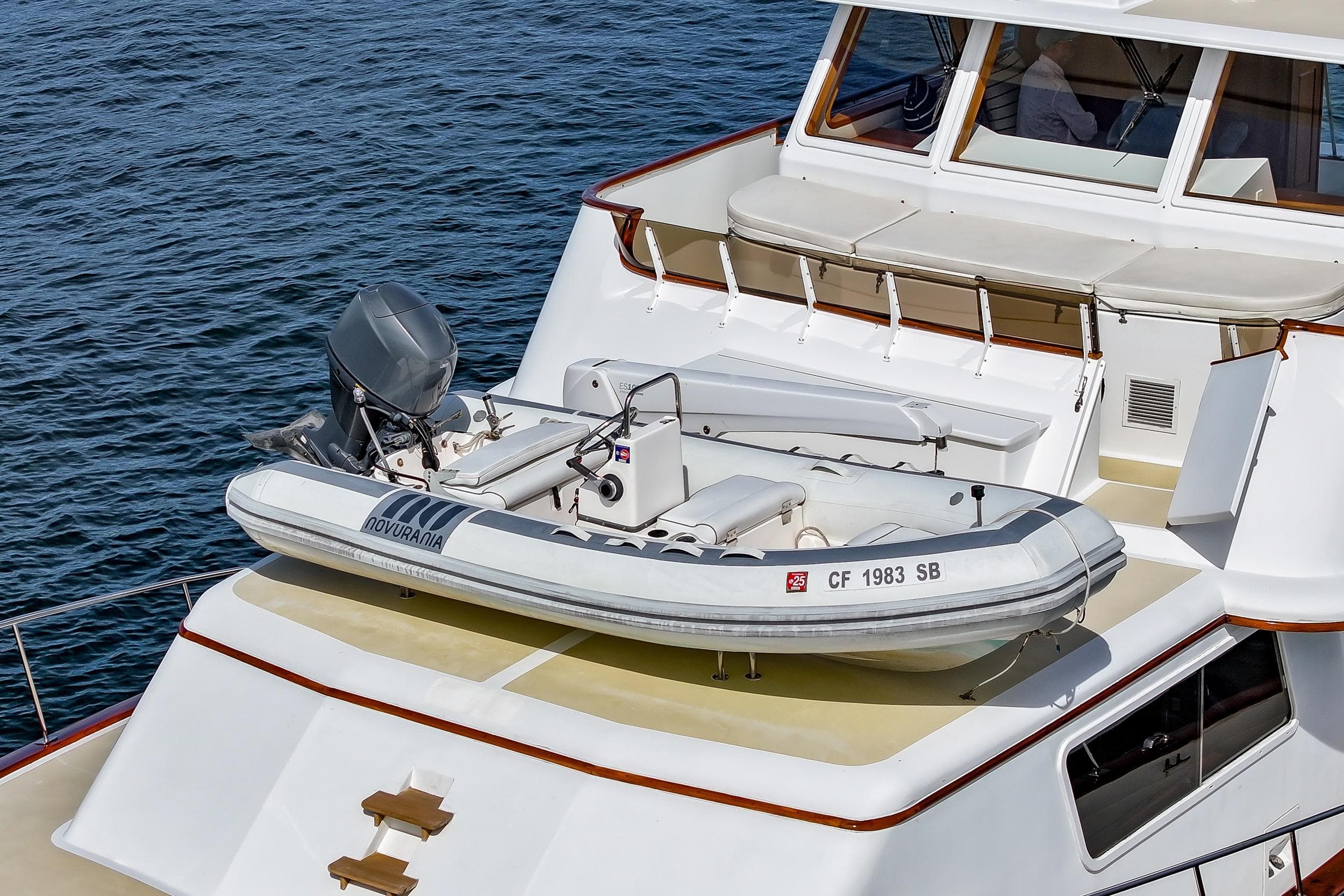 1970 Hargrave Yachtfisher with inflatable boat on deck, cruising on calm waters.