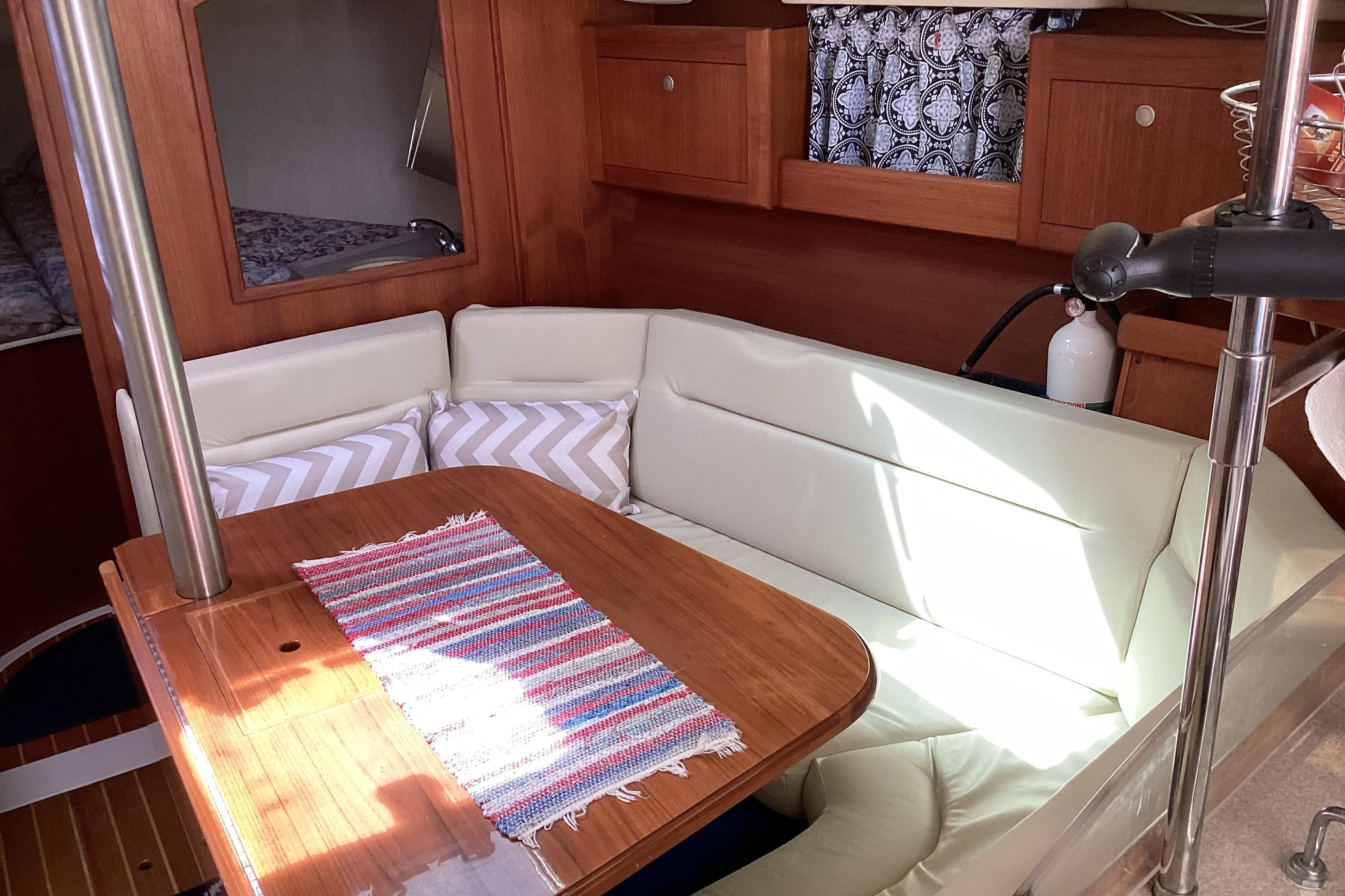 Cozy interior of 2001 Hunter 380 sailboat with cushioned seating and wooden table.