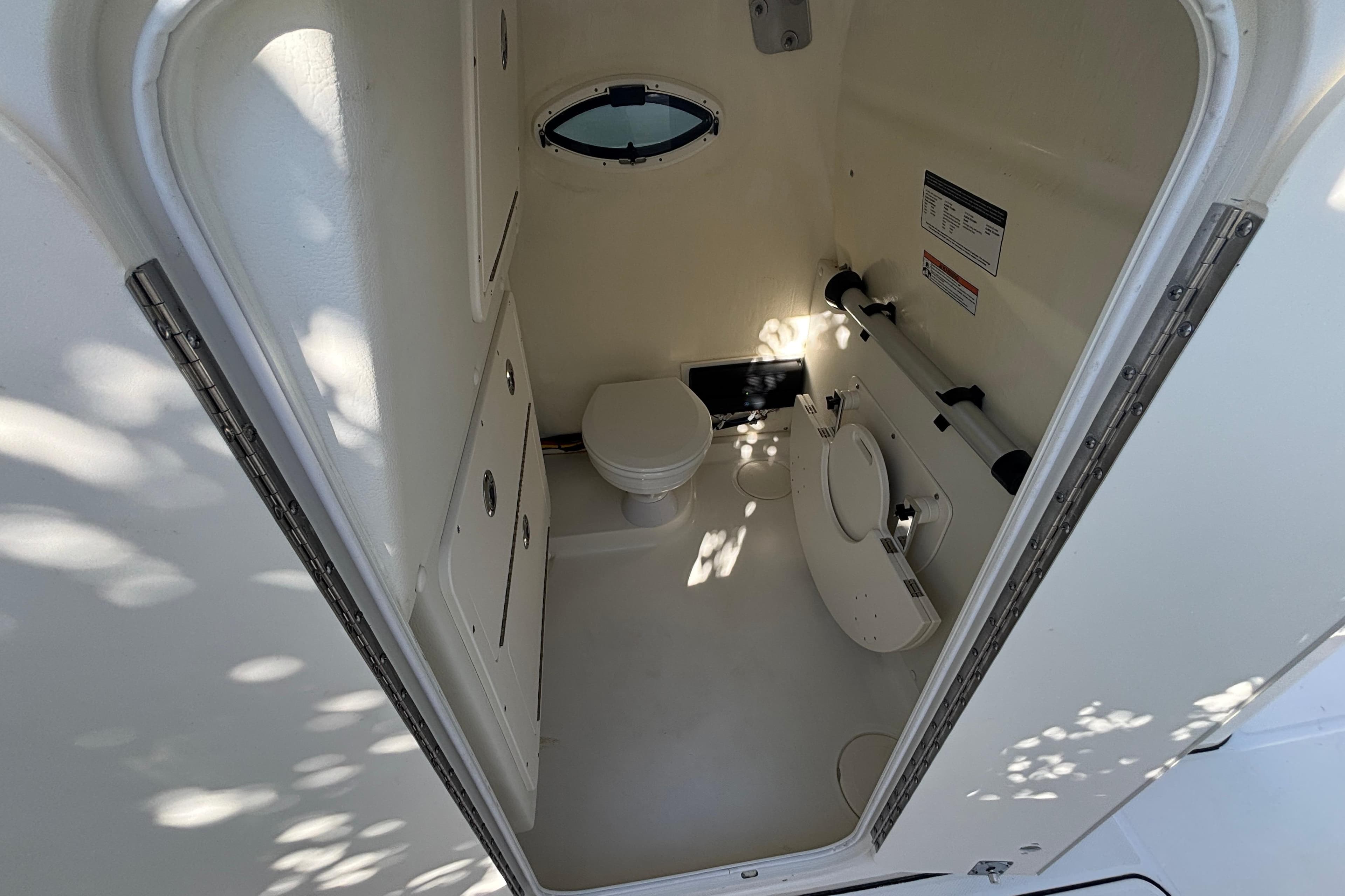 Interior of 2025 World Cat 325 CC boat bathroom with compact design and porthole window.