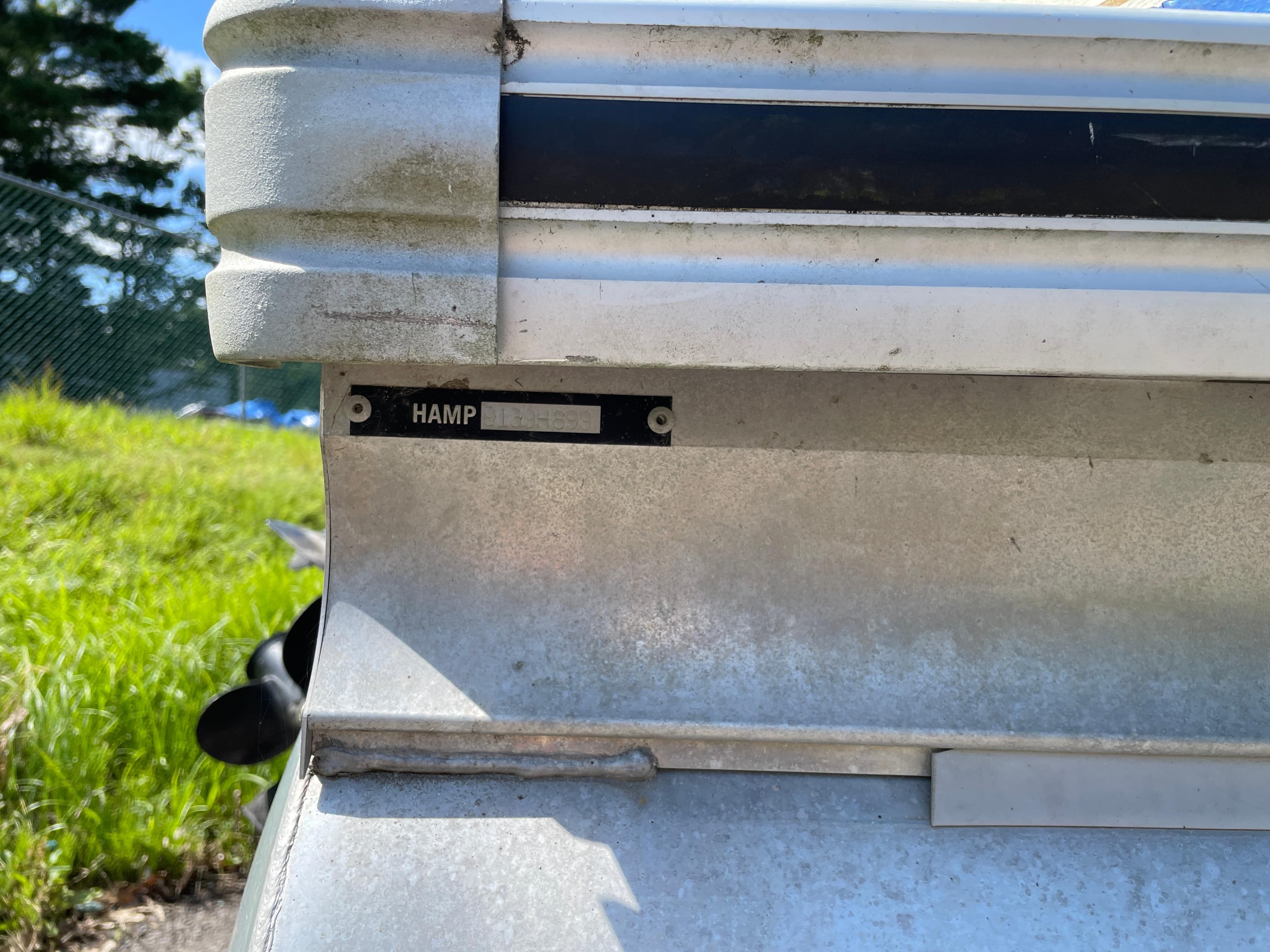 Close-up of a 1999 Harris Sunliner 240 boat's metal exterior with a nameplate.