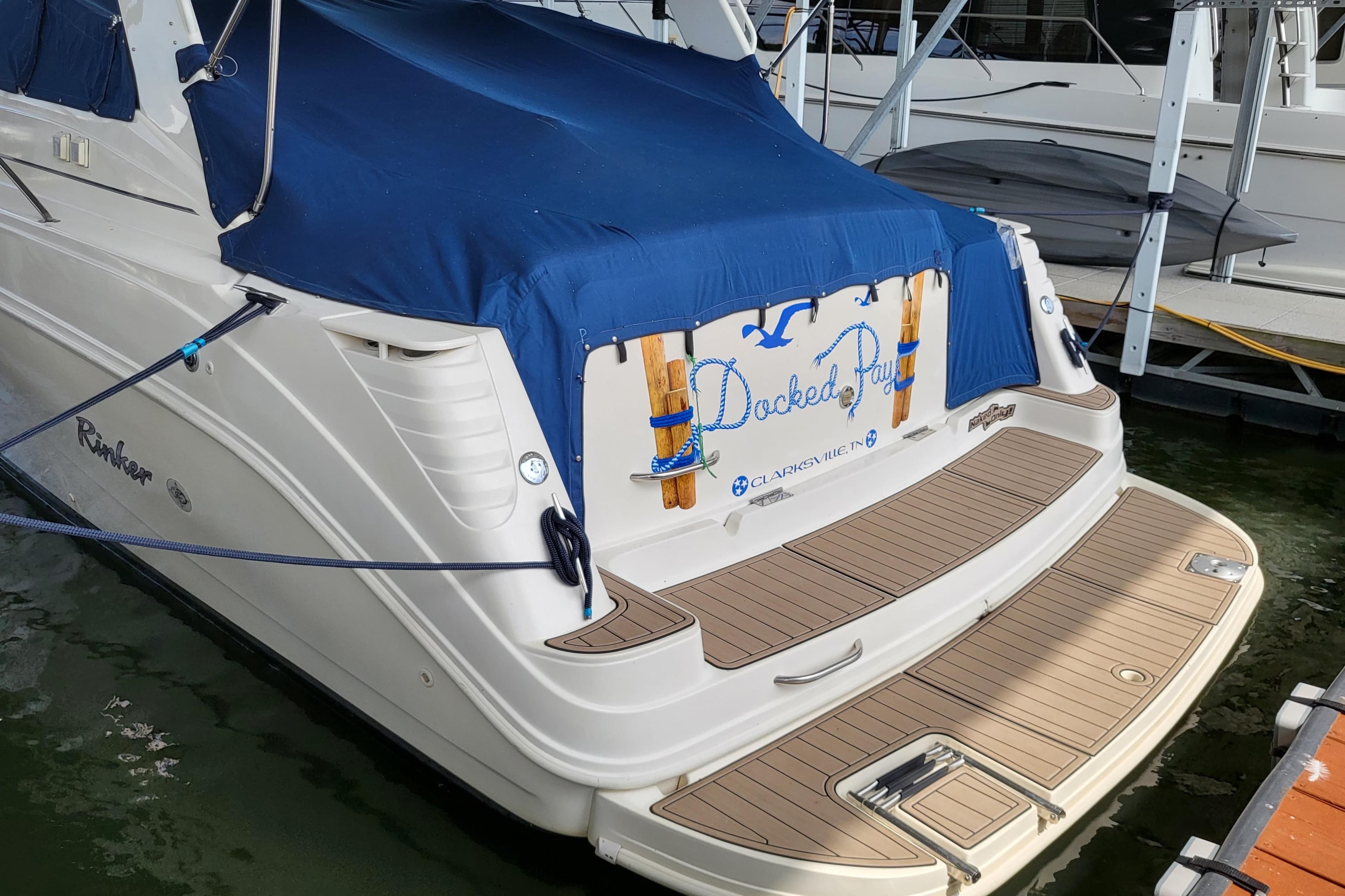 1999 Rinker Fiesta Vee 330 boat docked with blue cover and wooden deck.