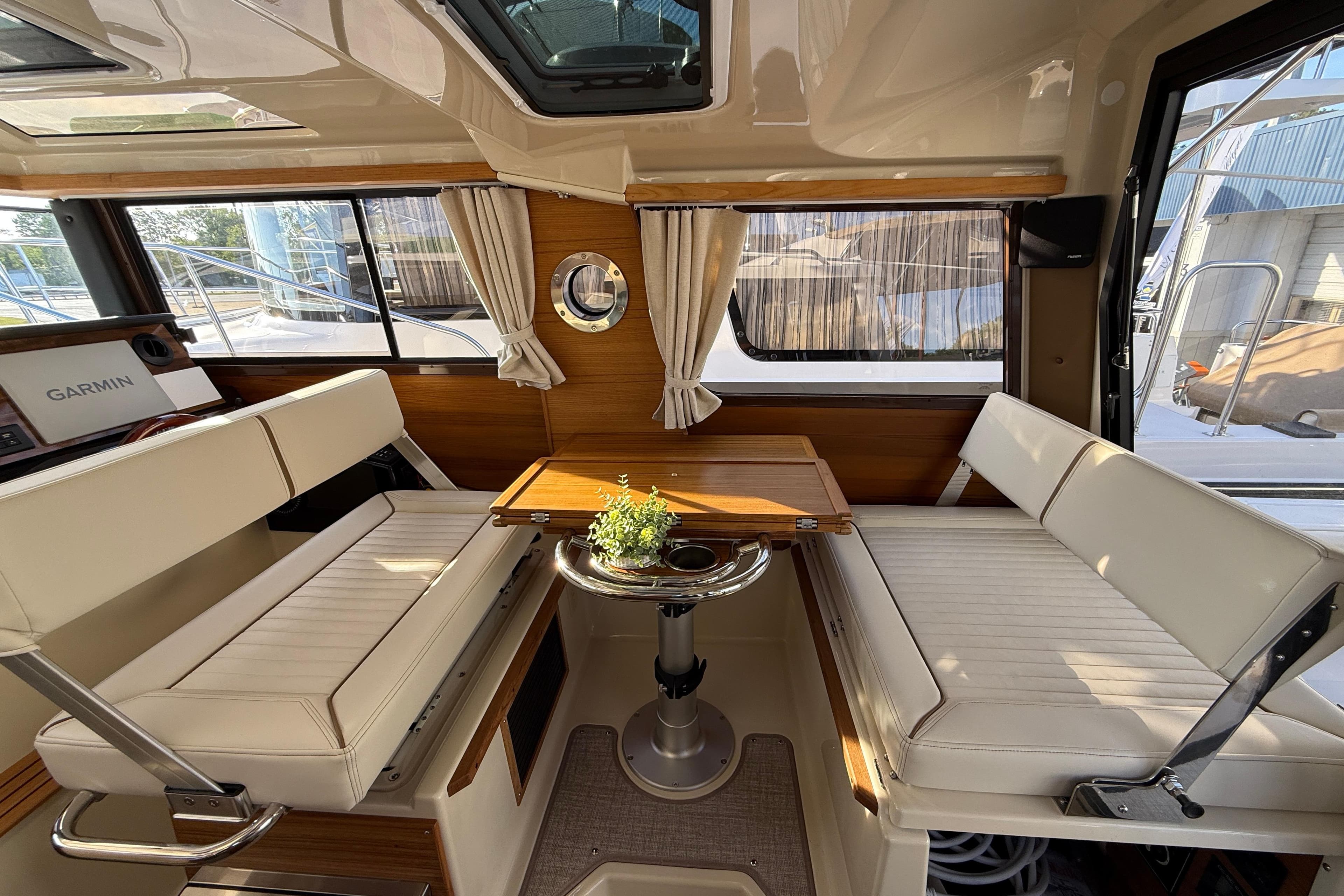 Interior of 2026 Ranger Tugs R-27, featuring cozy seating and a wooden table.