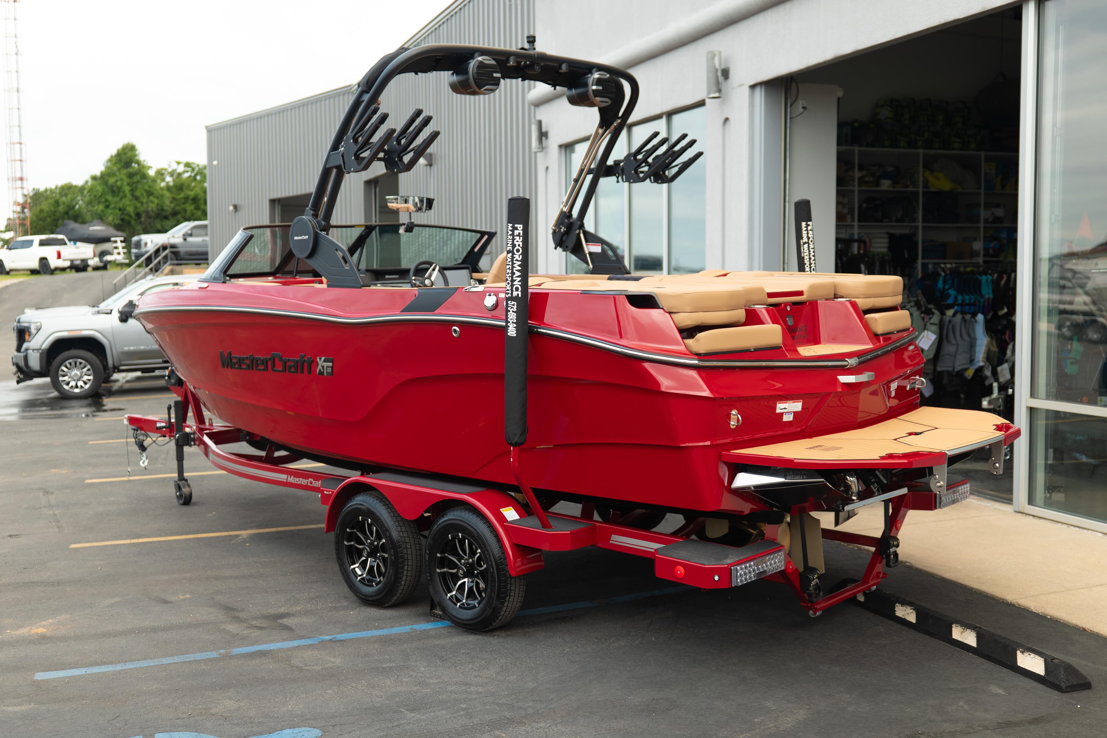 2026 MasterCraft XT23 boat in vibrant red, parked on a trailer outside a showroom.