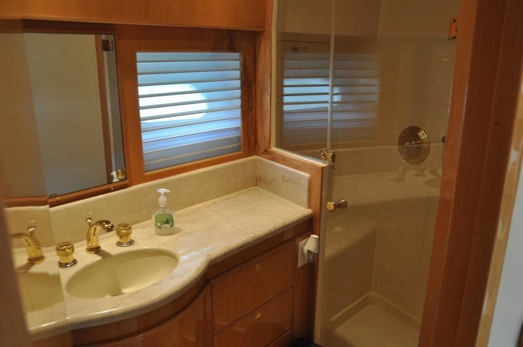Luxurious bathroom in a 2003 McKinna 58 yacht with marble countertop and gold fixtures.