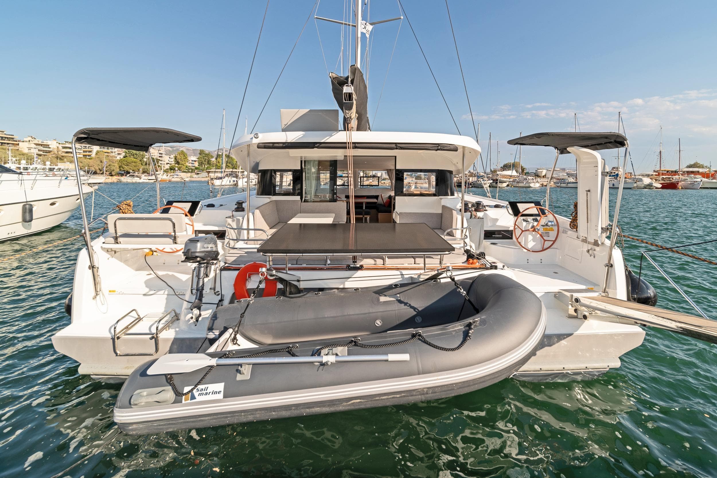 2024 Excess 14 catamaran docked with inflatable dinghy, showcasing spacious deck and modern design.