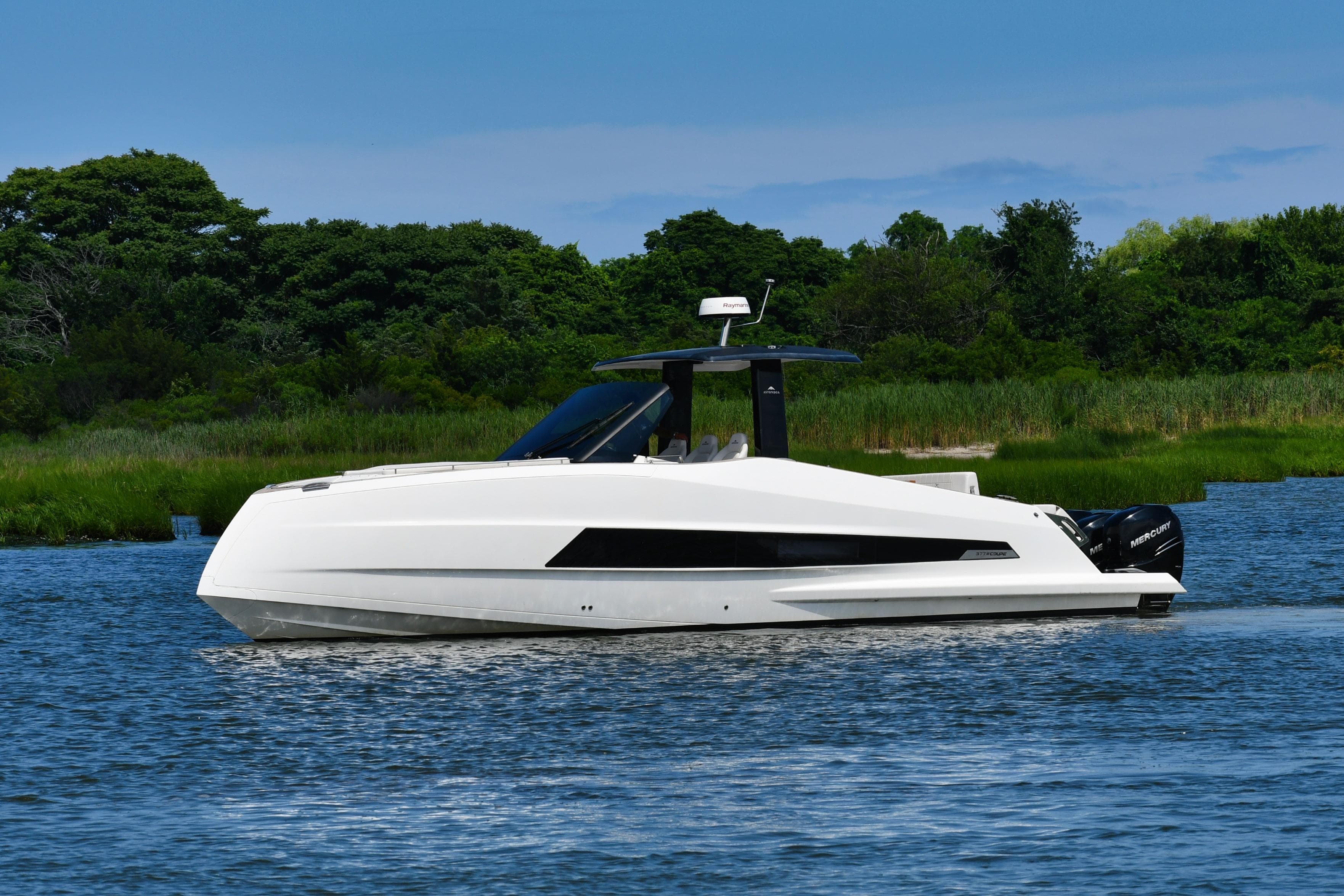 2023 Astondoa 377 Coupe Outboard yacht cruising on a serene lake with lush greenery.