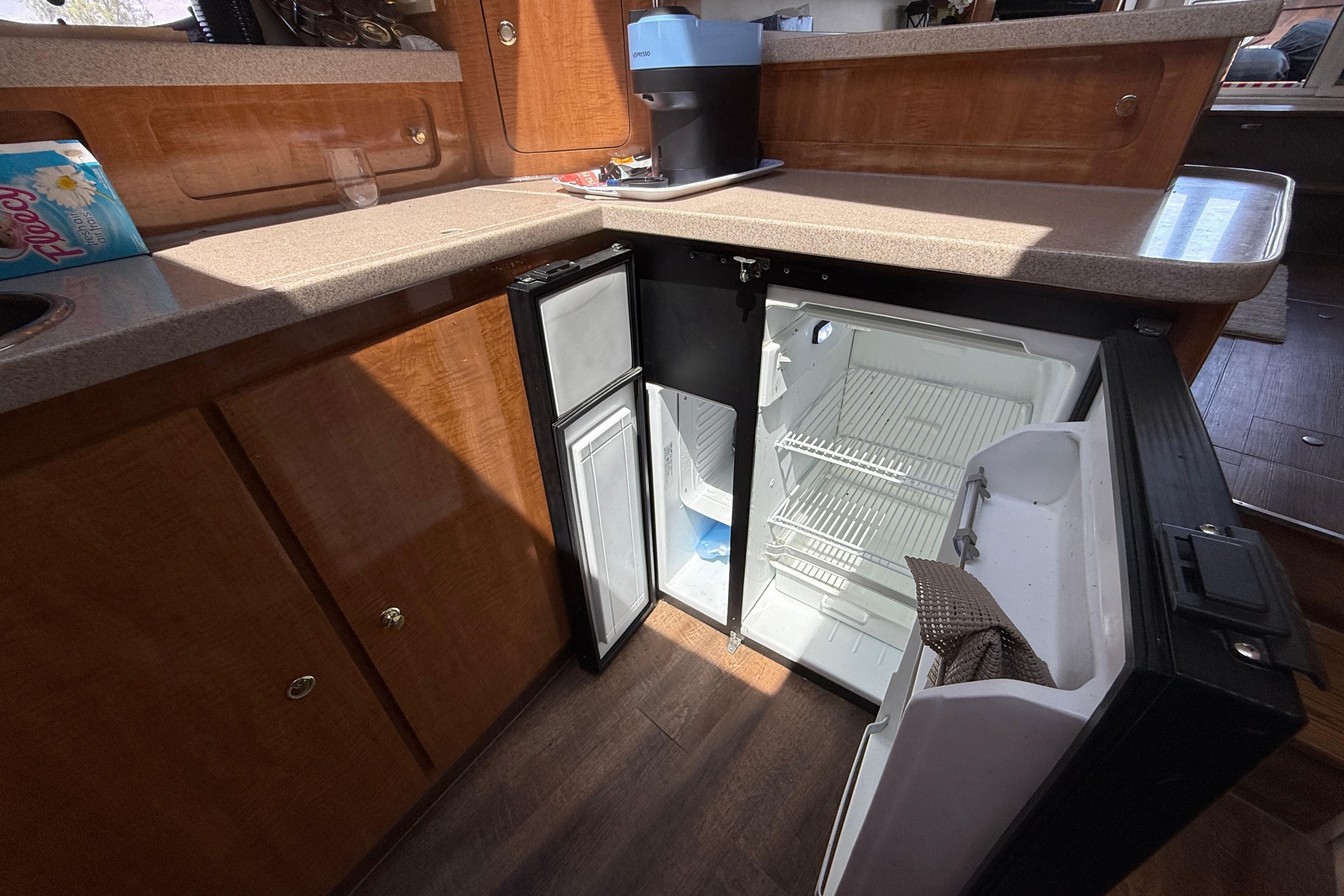 2001 Regal Commodore 3780 yacht interior with open mini fridge and wooden cabinetry.