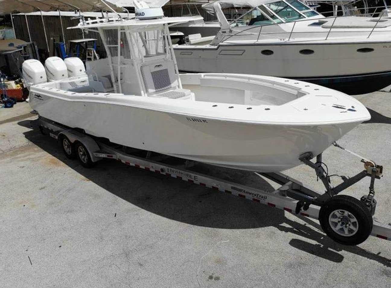 2008 Invincible 33 boat on trailer, triple engines, docked beside other boats.