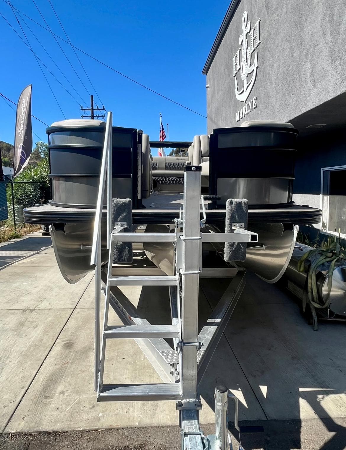 2025 Barletta Lusso 23UC pontoon boat on trailer outside marine dealership.