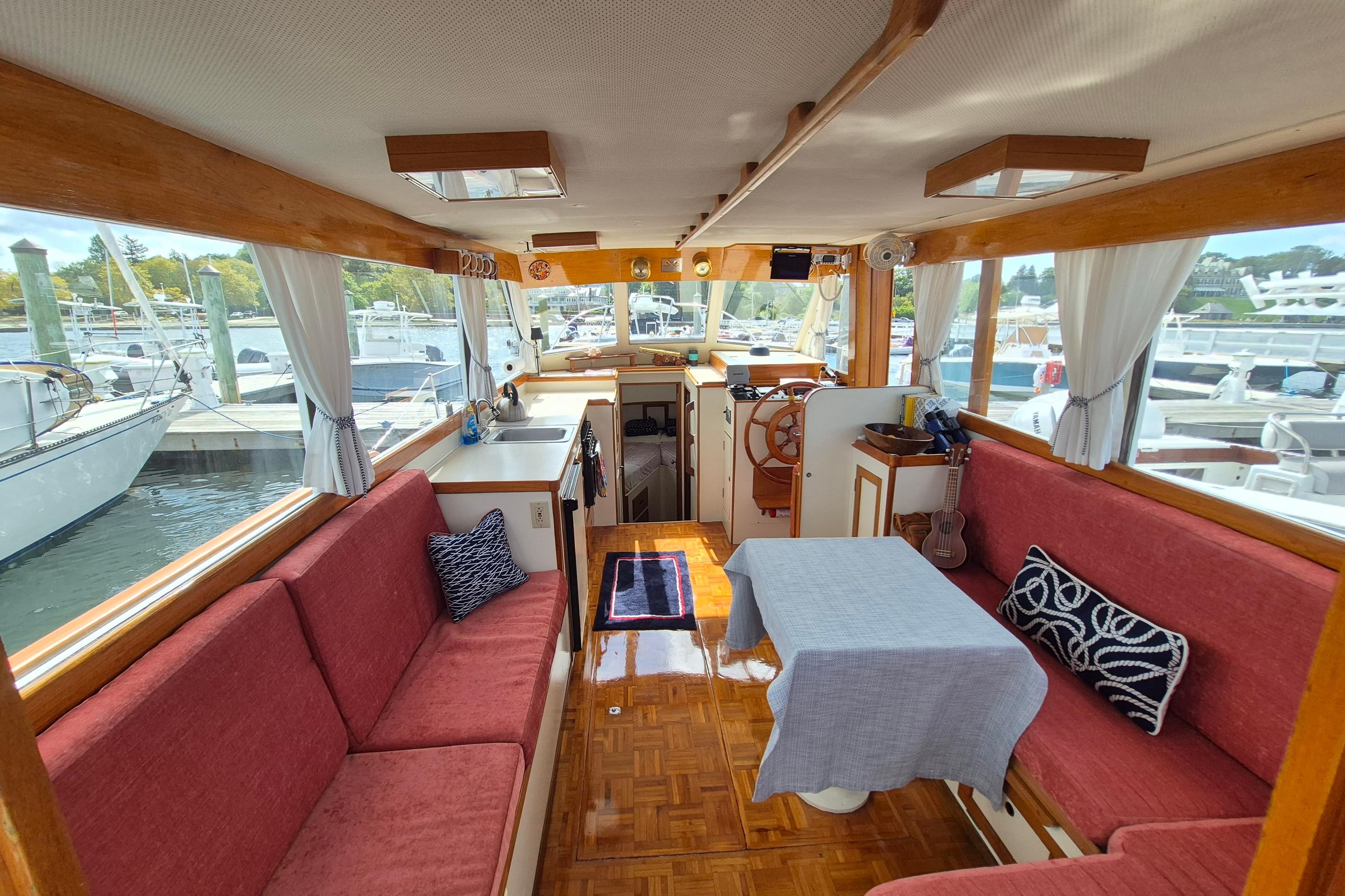 Interior of 1986 Island Gypsy 32 Sedan Trawler with red seating and wooden accents.