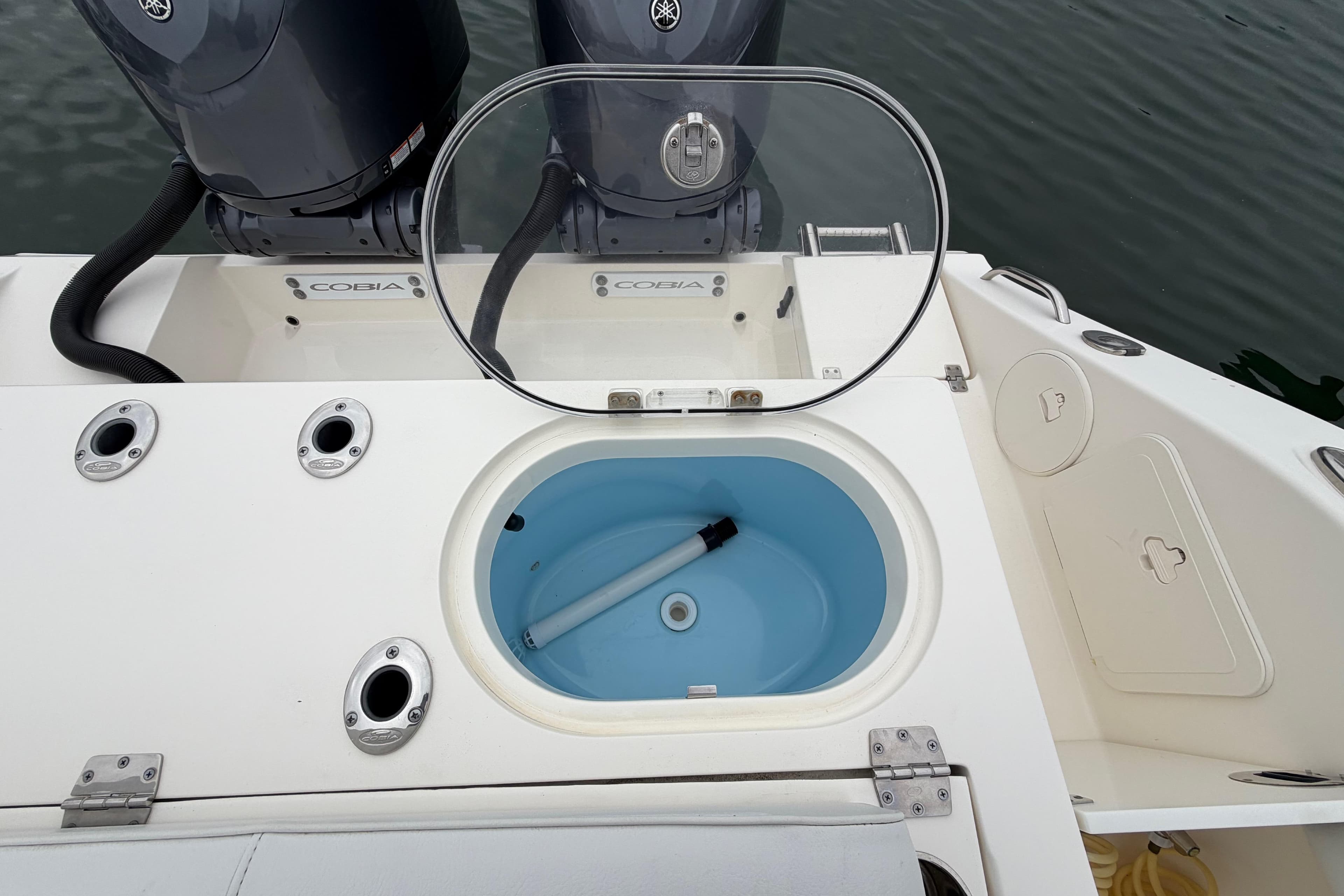 2023 Cobia 301 Center Console boat with open livewell and dual outboard motors.