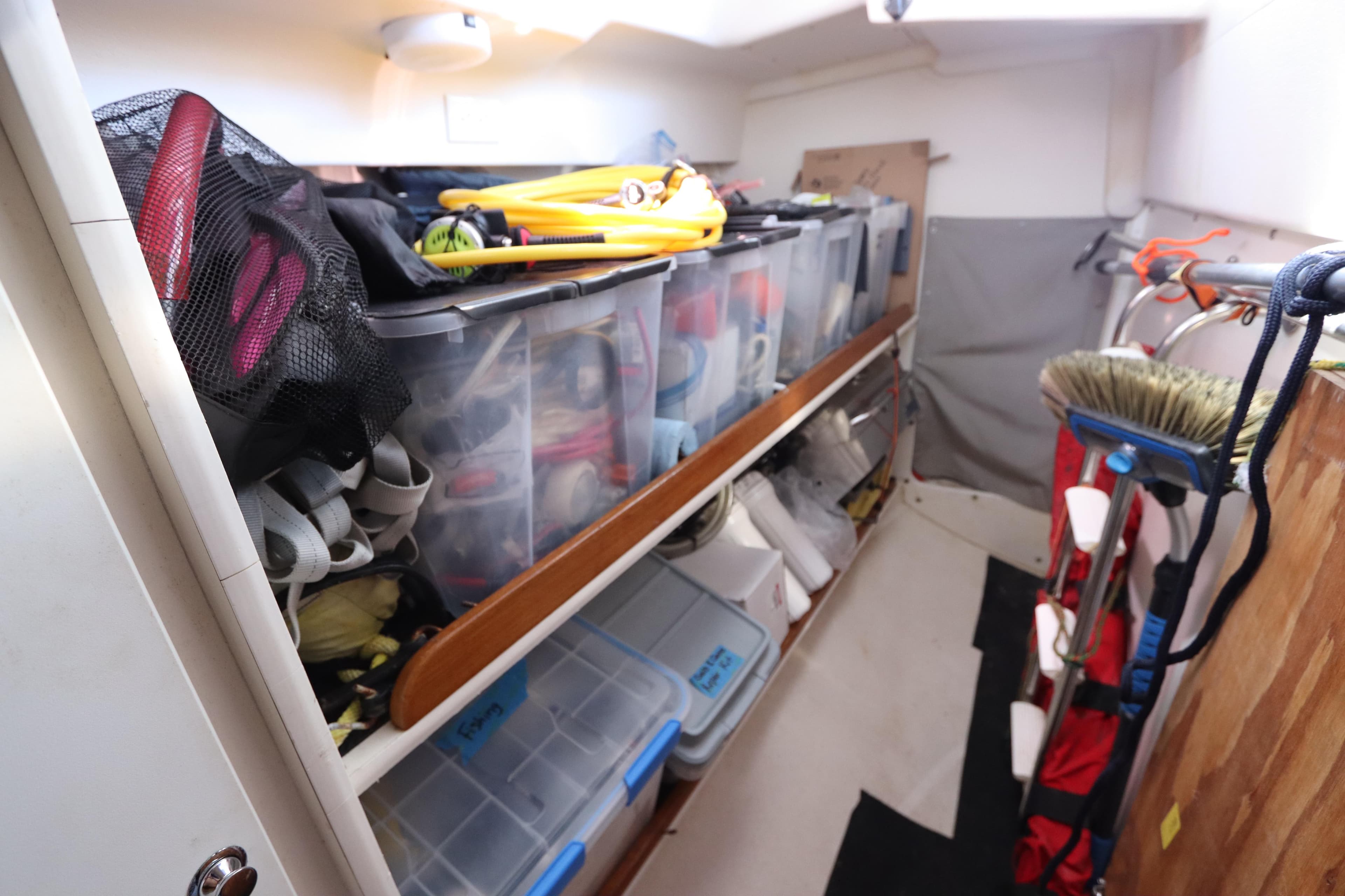 Storage area in a 2007 Catalina Morgan 440 sailboat, featuring organized bins and cleaning tools.