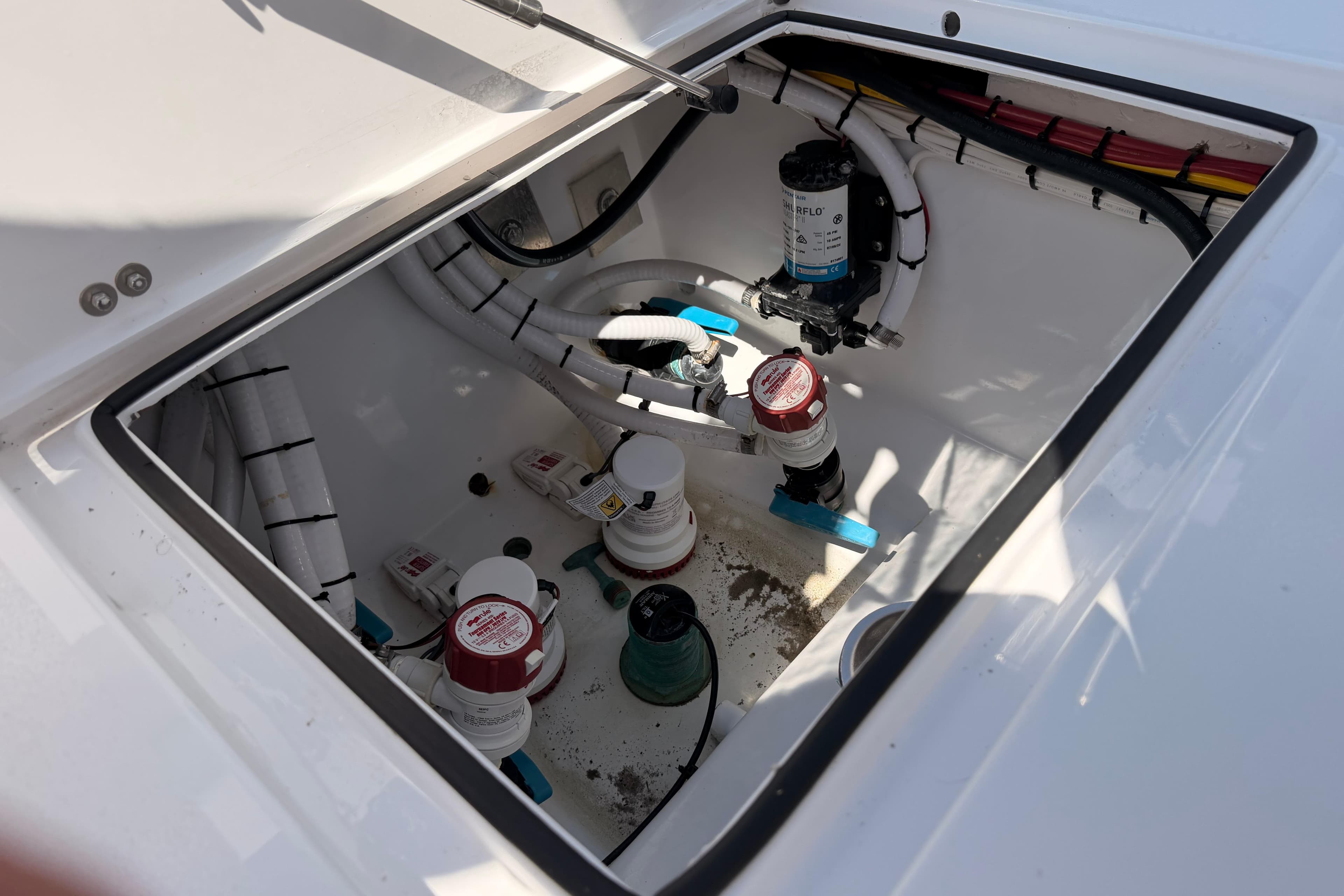 2024 Stoner 23 CC boat compartment with plumbing and wiring components.