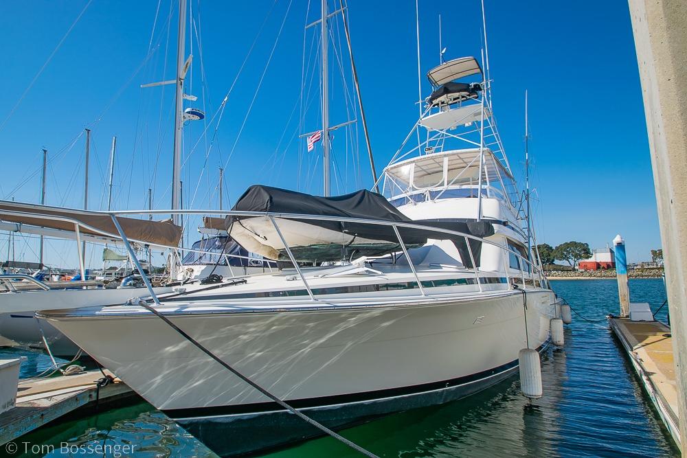 1989 Bertram 50 Convertible yacht docked in a marina under clear blue skies.