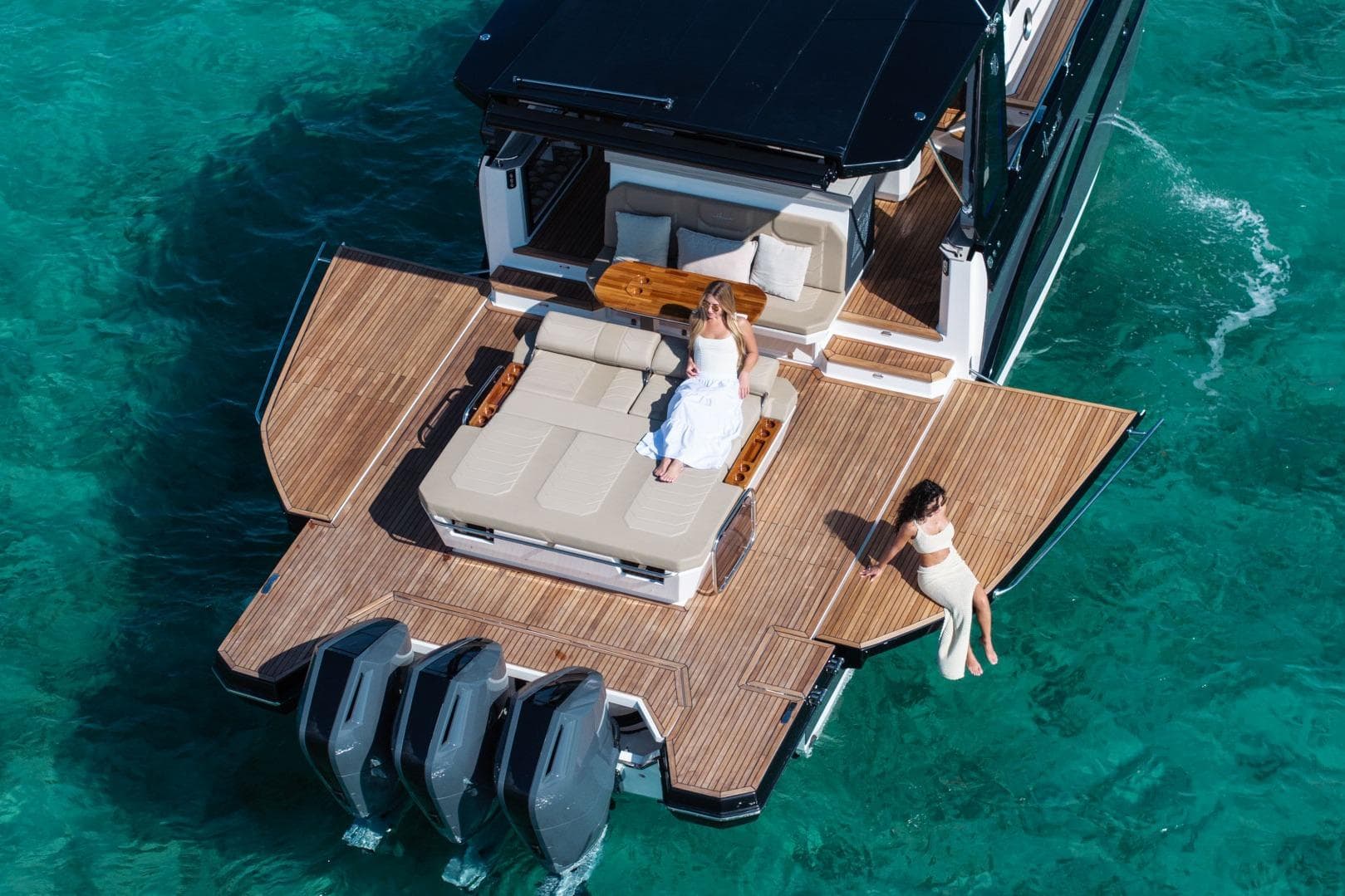 Luxury Hanover 447 yacht, 2026 model, with two people relaxing on deck in turquoise waters.