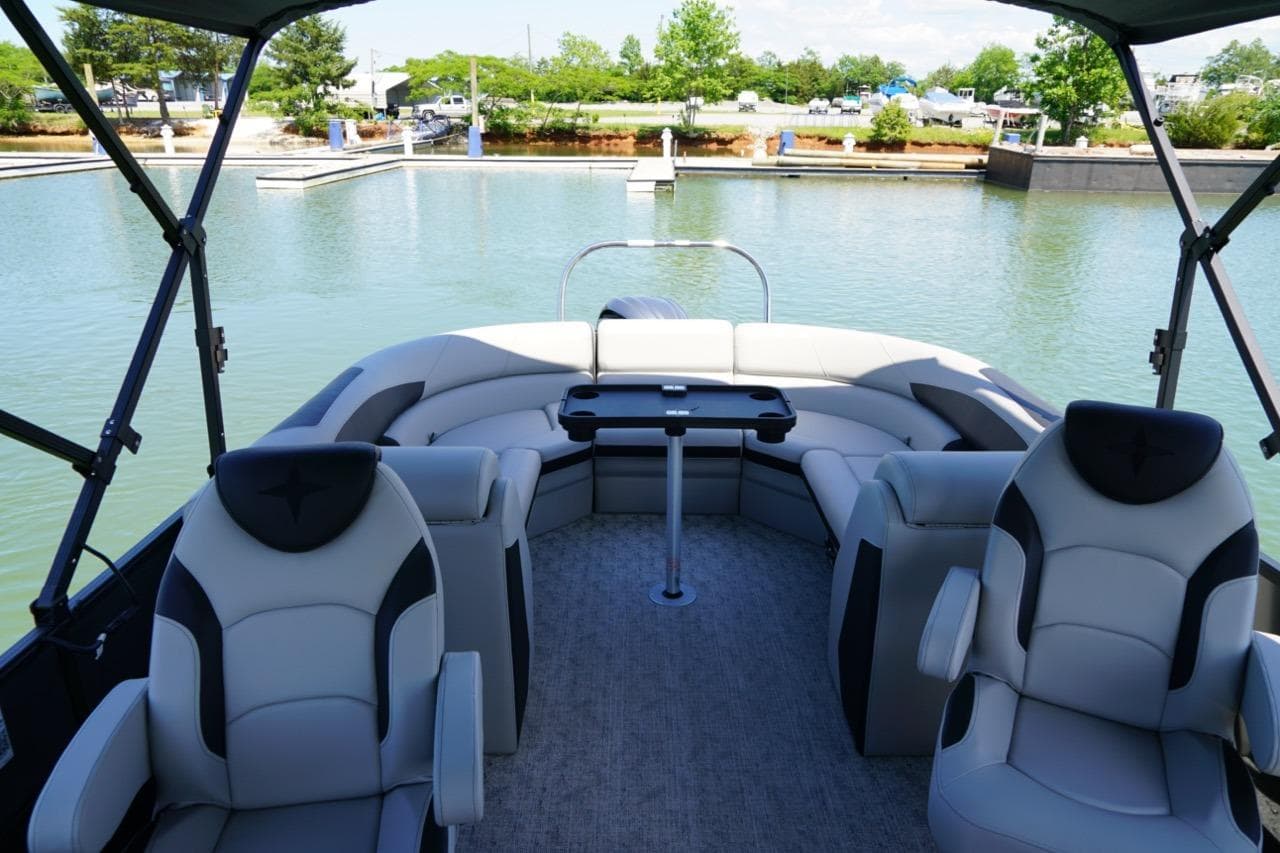 2026 Berkshire 24 RFX LE pontoon boat interior with plush seating and table on calm water.