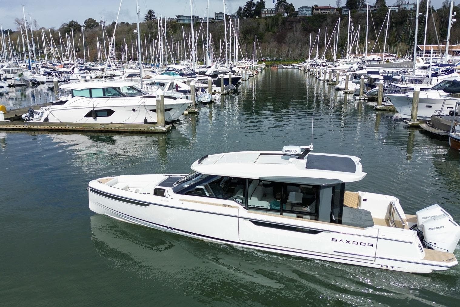2026 Saxdor 400 GTC luxury boat docked in a marina with numerous sailboats.