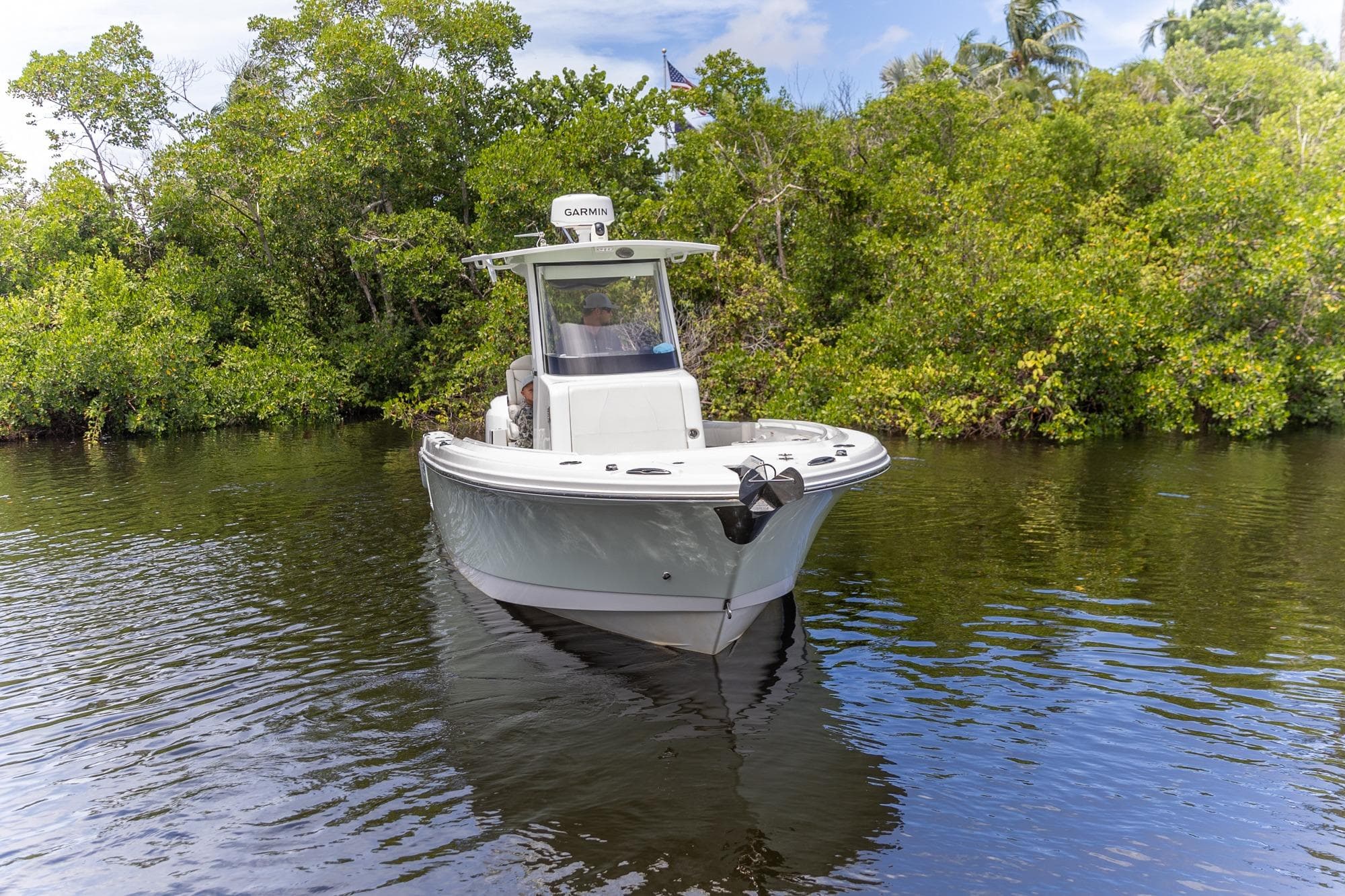2023 Edgewater 262CC boat navigating a calm river surrounded by lush greenery.
