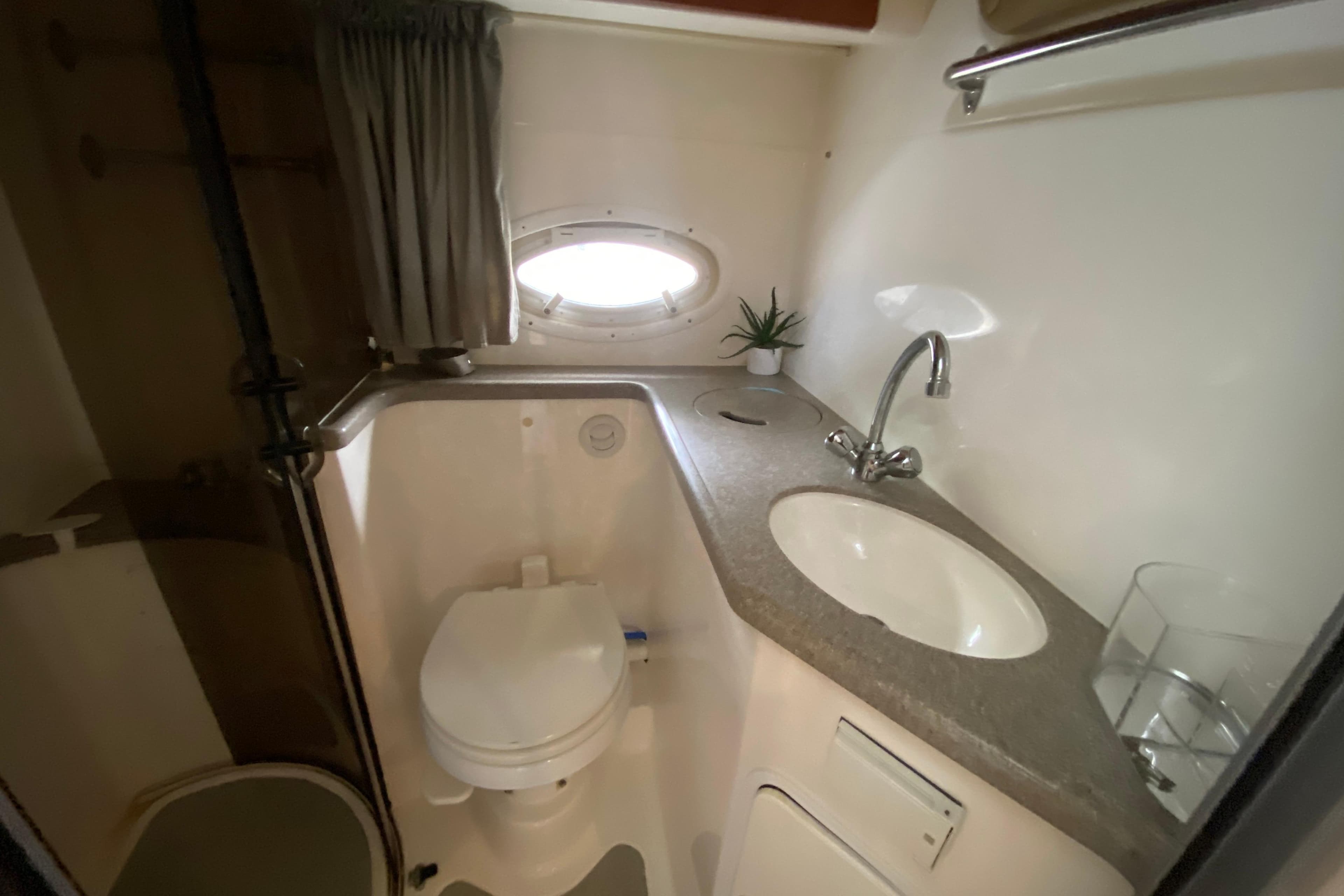 2008 Rinker 350 Express Cruiser bathroom with sink, toilet, and porthole window.