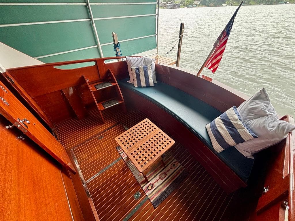 1954 Chris-Craft Sedan Cruiser interior with wooden seating, cushions, and American flag.