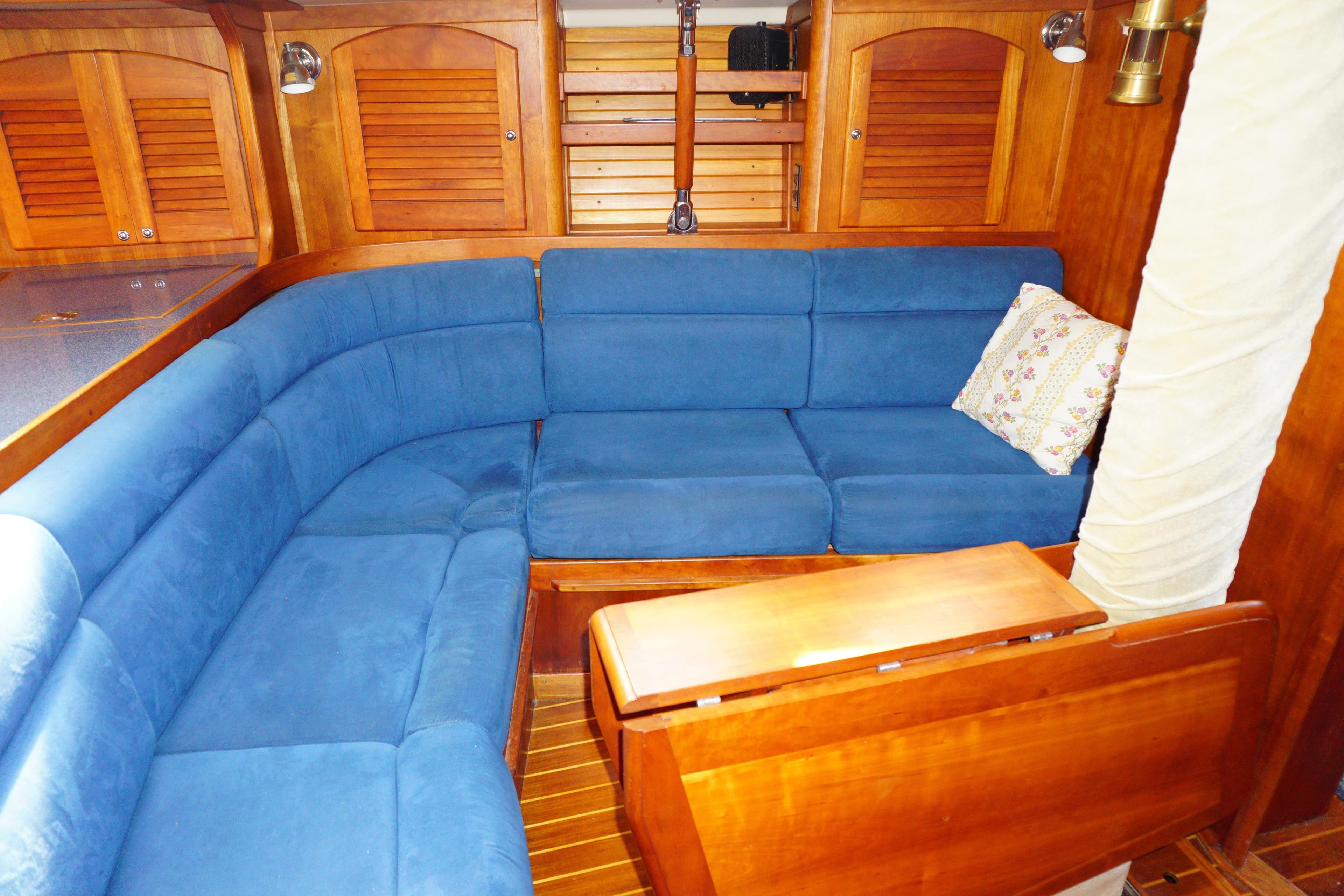 Interior of 1998 Sabre 402 yacht with blue cushioned seating and wooden accents.