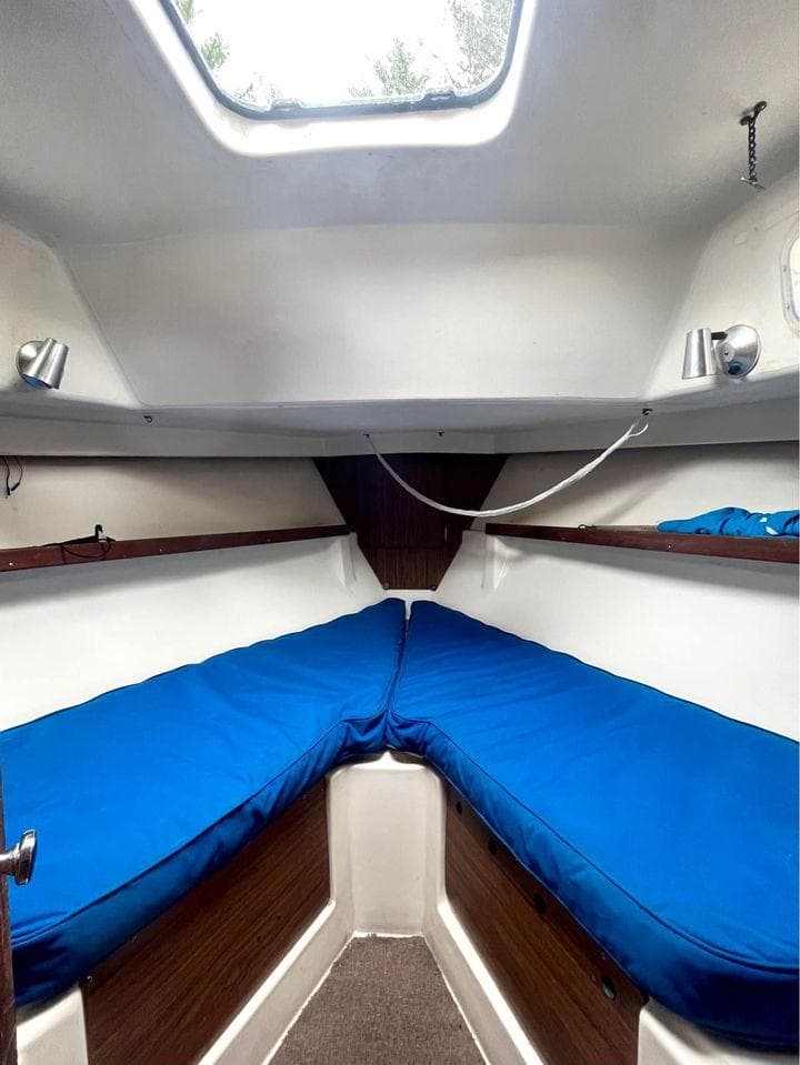 Interior cabin of 1977 Seafarer 38 sailboat with blue cushions and wooden accents.