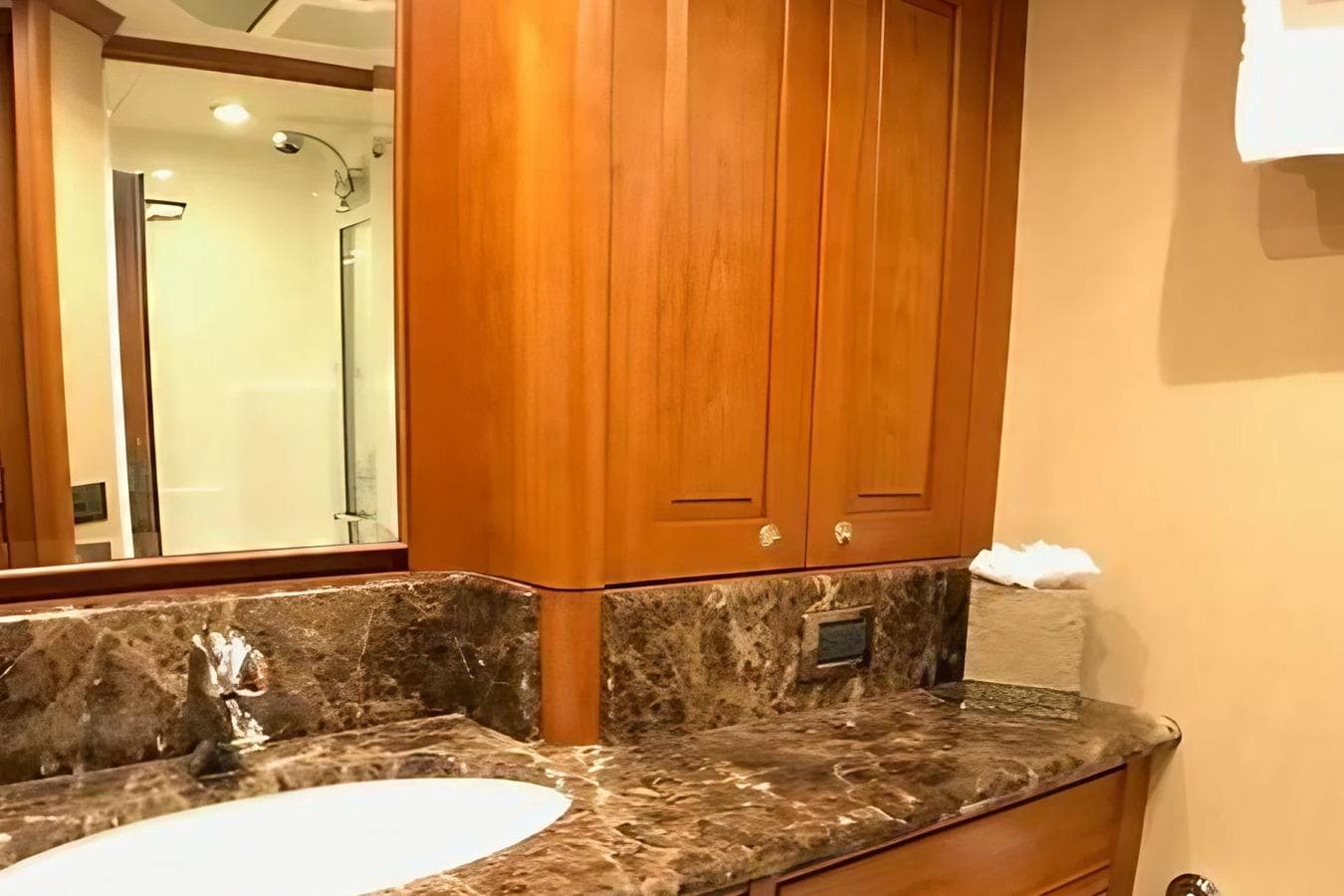 Luxurious bathroom in 2005 Pacific Mariner yacht with marble countertop and wooden cabinetry.