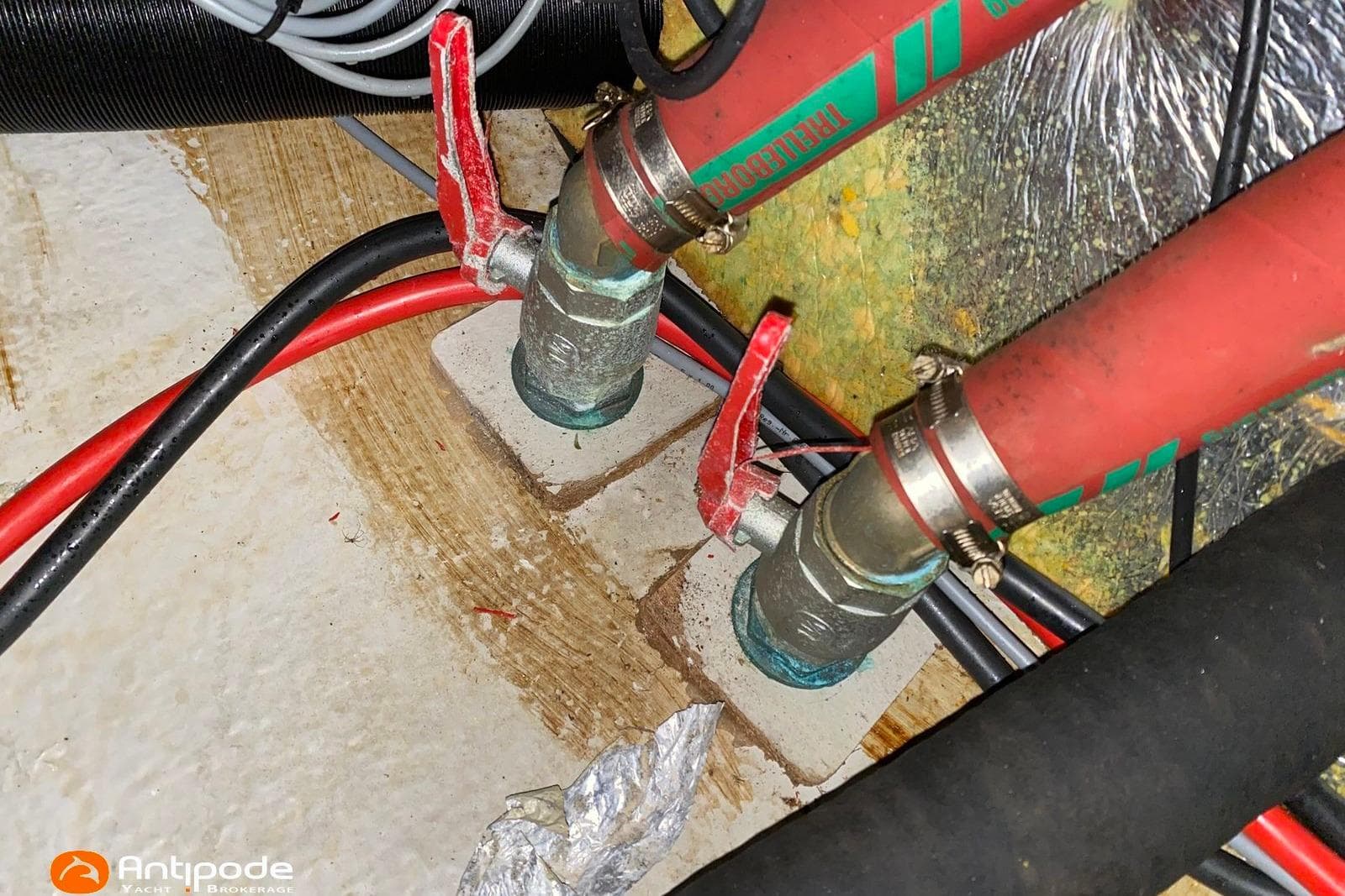 Red and black hoses with valves in a 1992 Hallberg-Rassy 36 yacht.