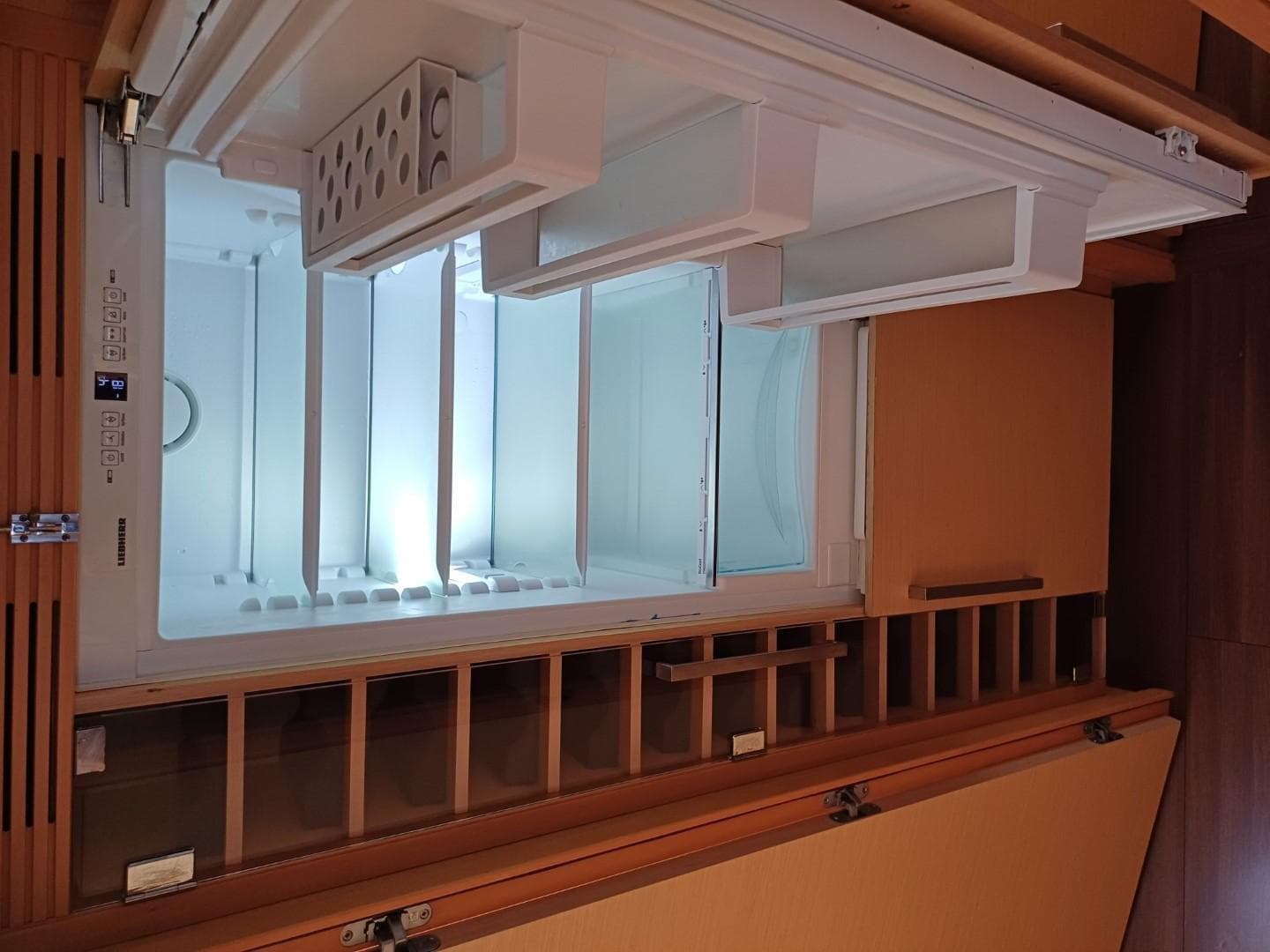 Open refrigerator inside a 2012 Lagoon 560 yacht, featuring wooden cabinetry.