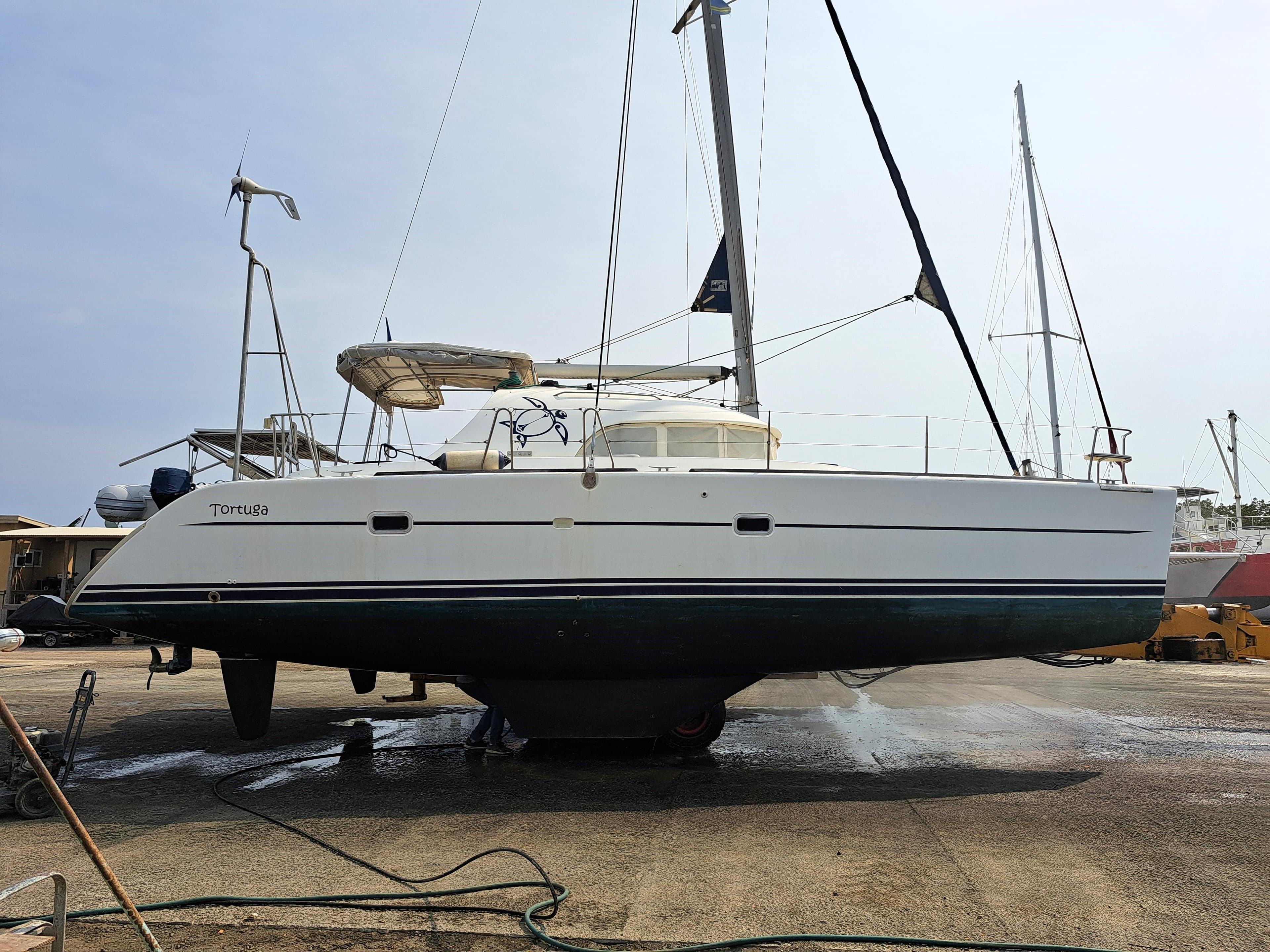 2001 Lagoon 380 catamaran on dry dock, side view, with sails and equipment visible.