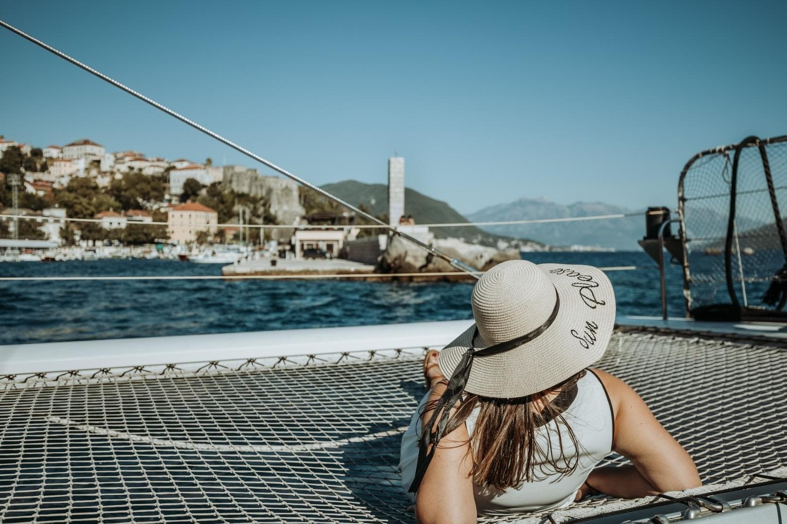 Woman relaxing on 2015 Fountaine Pajot TAHITI catamaran, scenic coastal view.