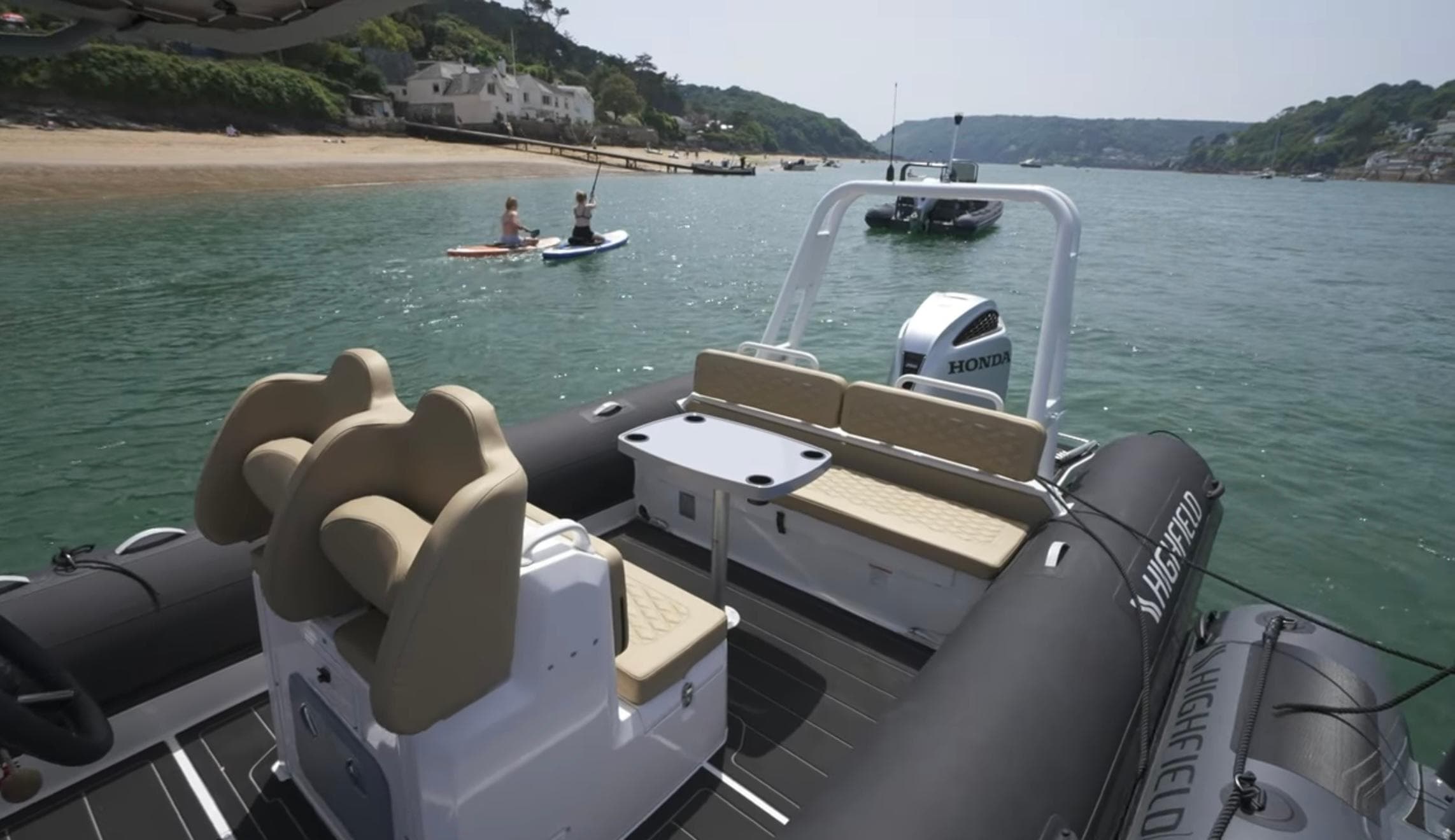 Highfield Sport 760 boat, 2025 model, on water near beach with paddleboarders.