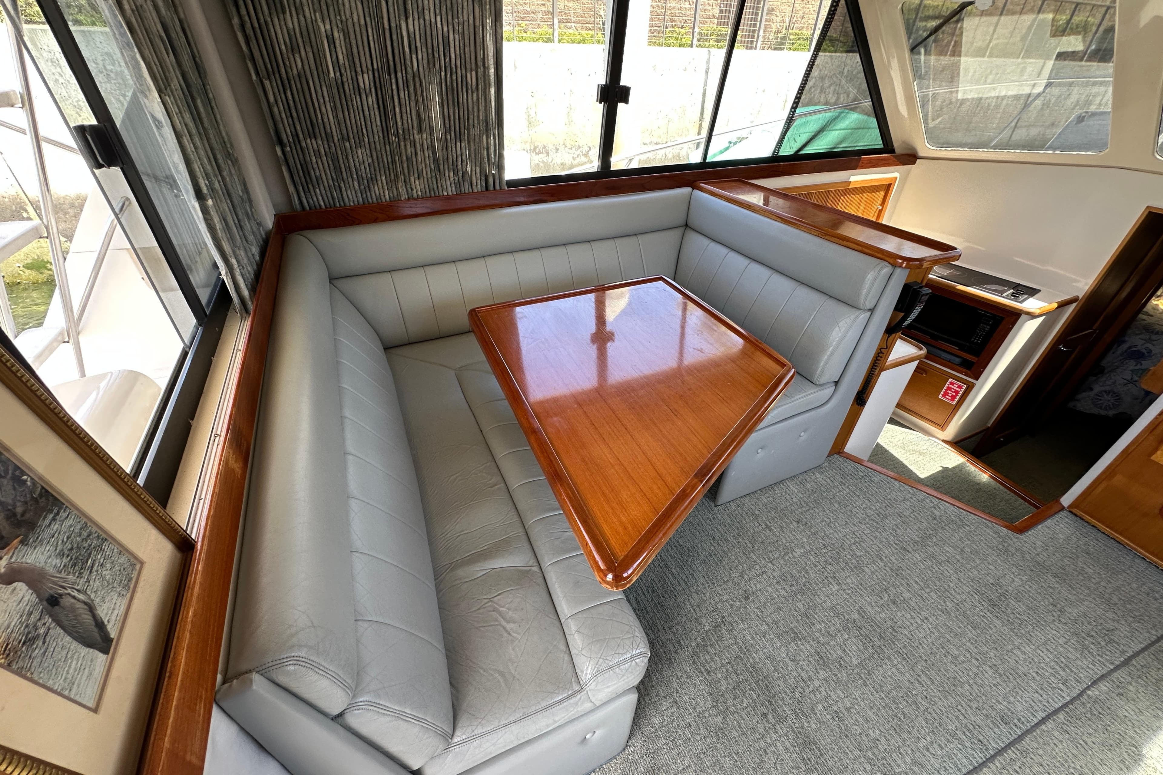 Interior of 1999 Riviera 3600 Sport Yacht with plush seating and wooden table.