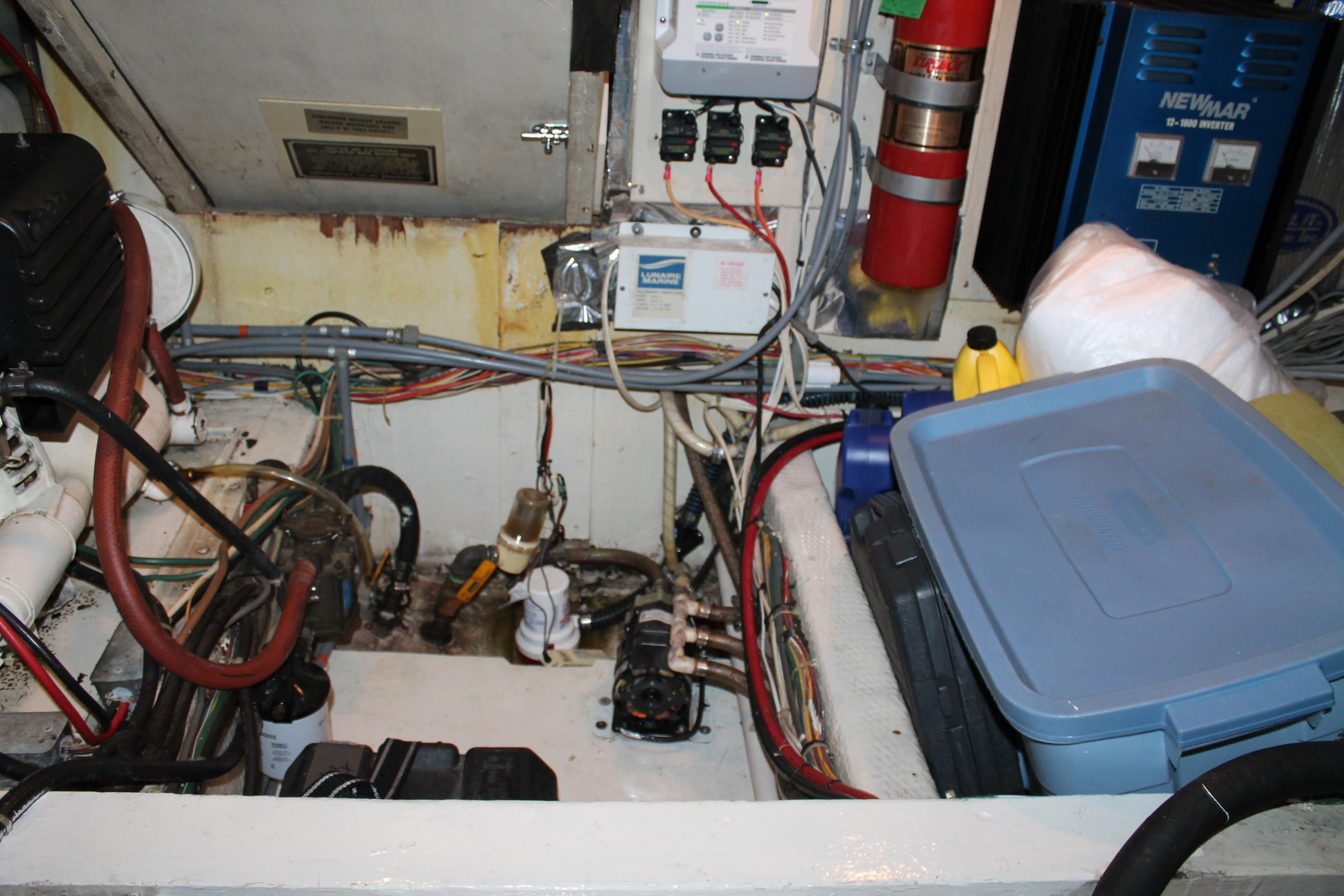 Engine room of 1987 Chris-Craft 427 Catalina with wiring, equipment, and storage containers.