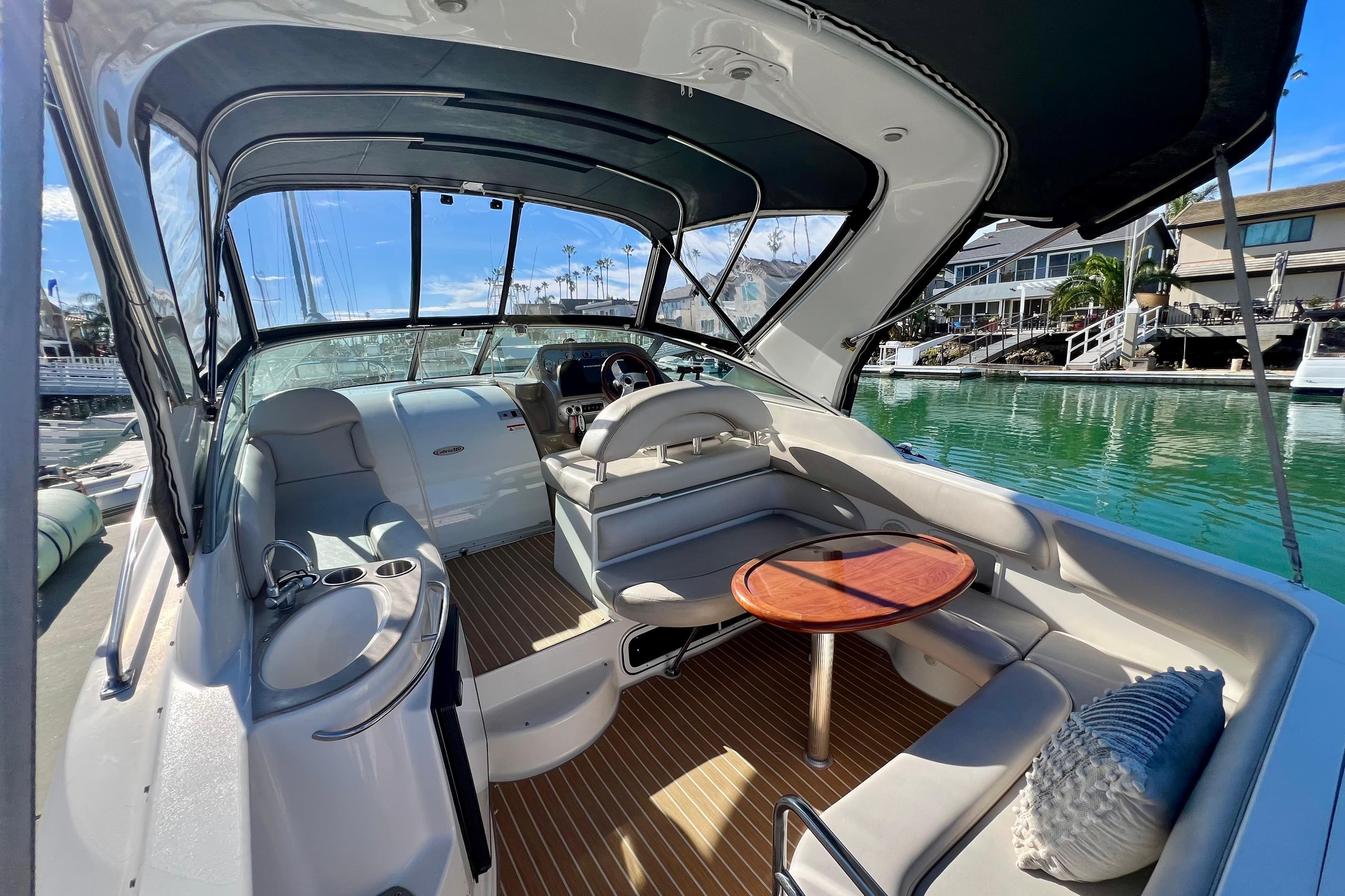 2007 Larson Cabrio 310 boat interior with seating and table, docked by waterfront homes.