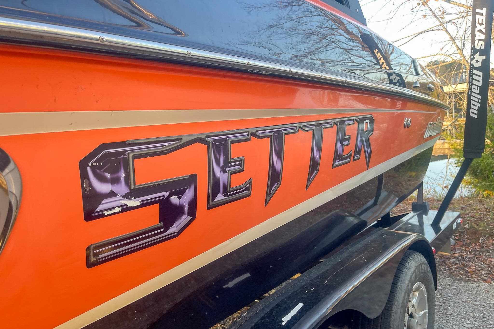 2011 Malibu Wakesetter 21 VLX boat with orange and black design on trailer.