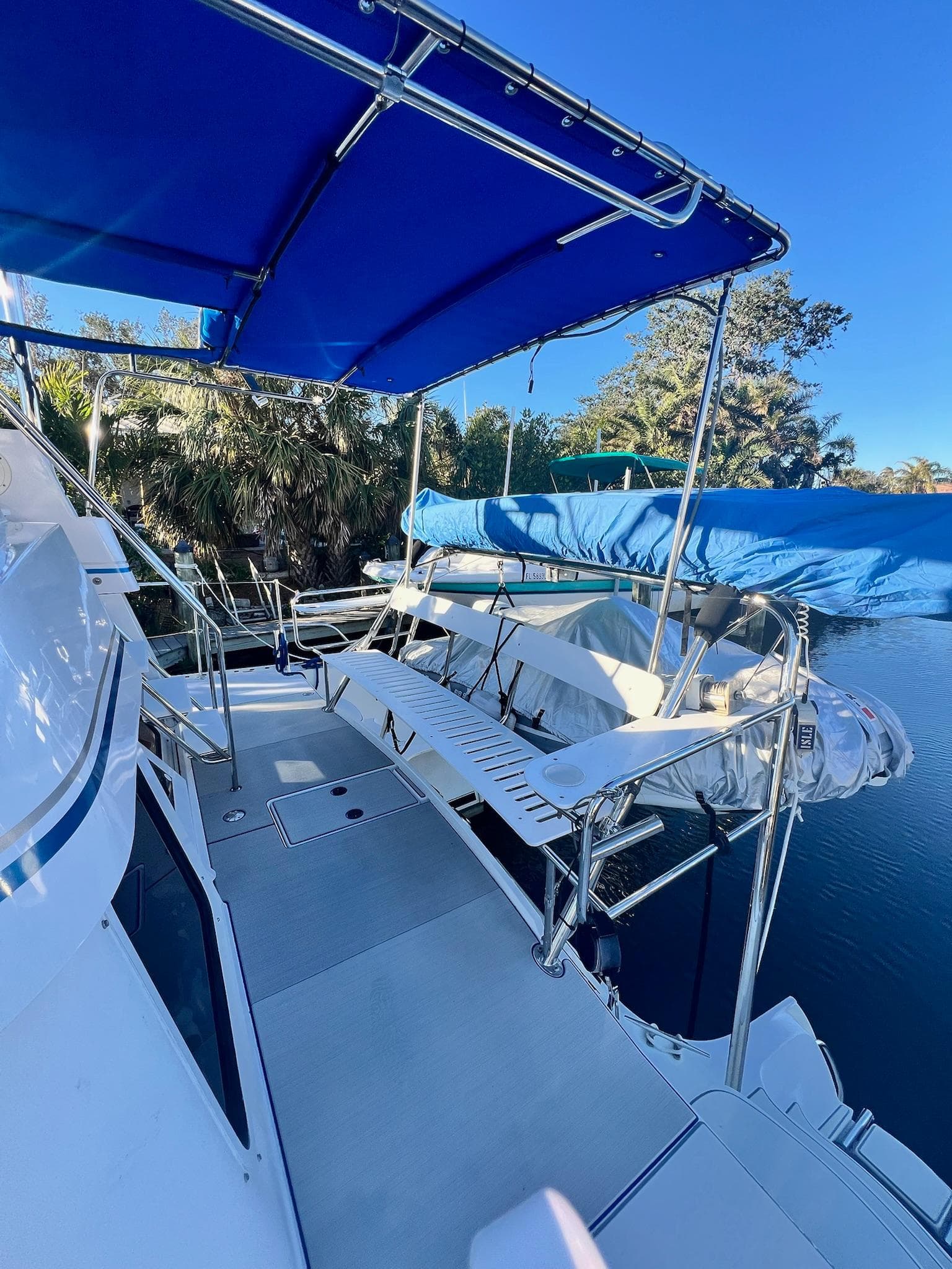 2006 PDQ MV34 boat deck with blue canopy and seating, docked by water.