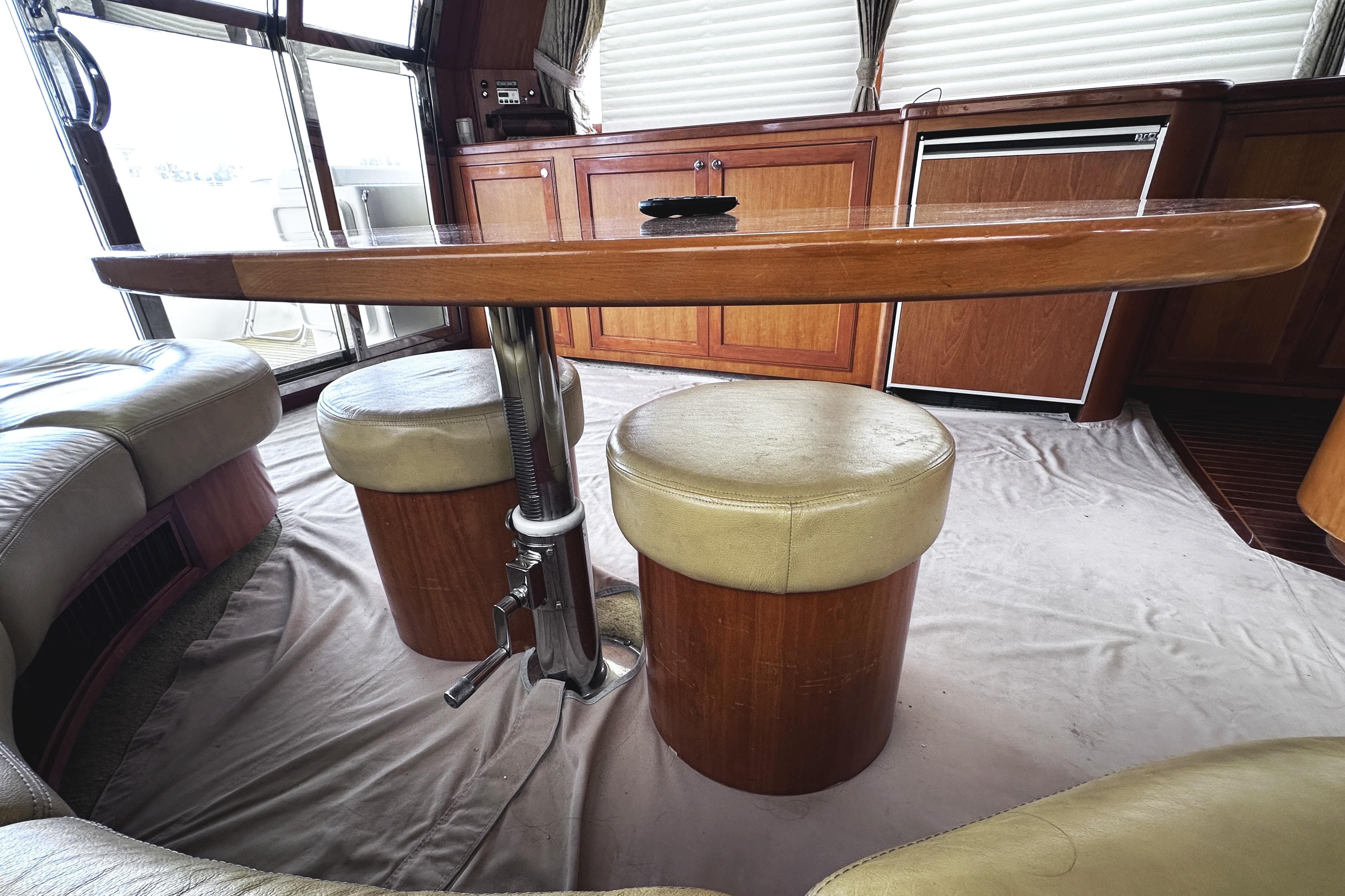 Interior of 2004 McKinna 57 PHMY yacht with wooden table and cushioned seating.
