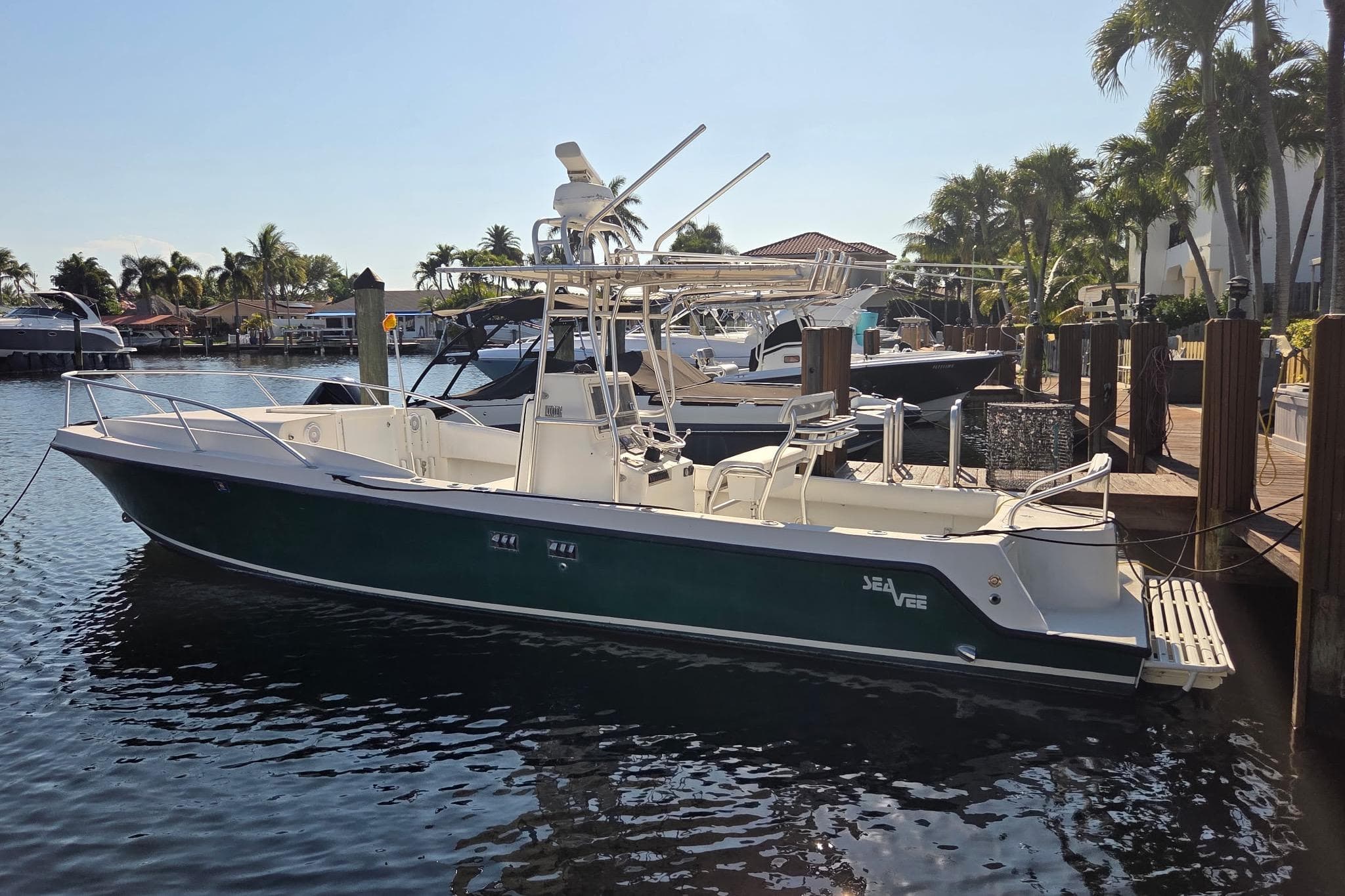 2000 SeaVee 290B boat docked in a sunny marina, surrounded by palm trees.