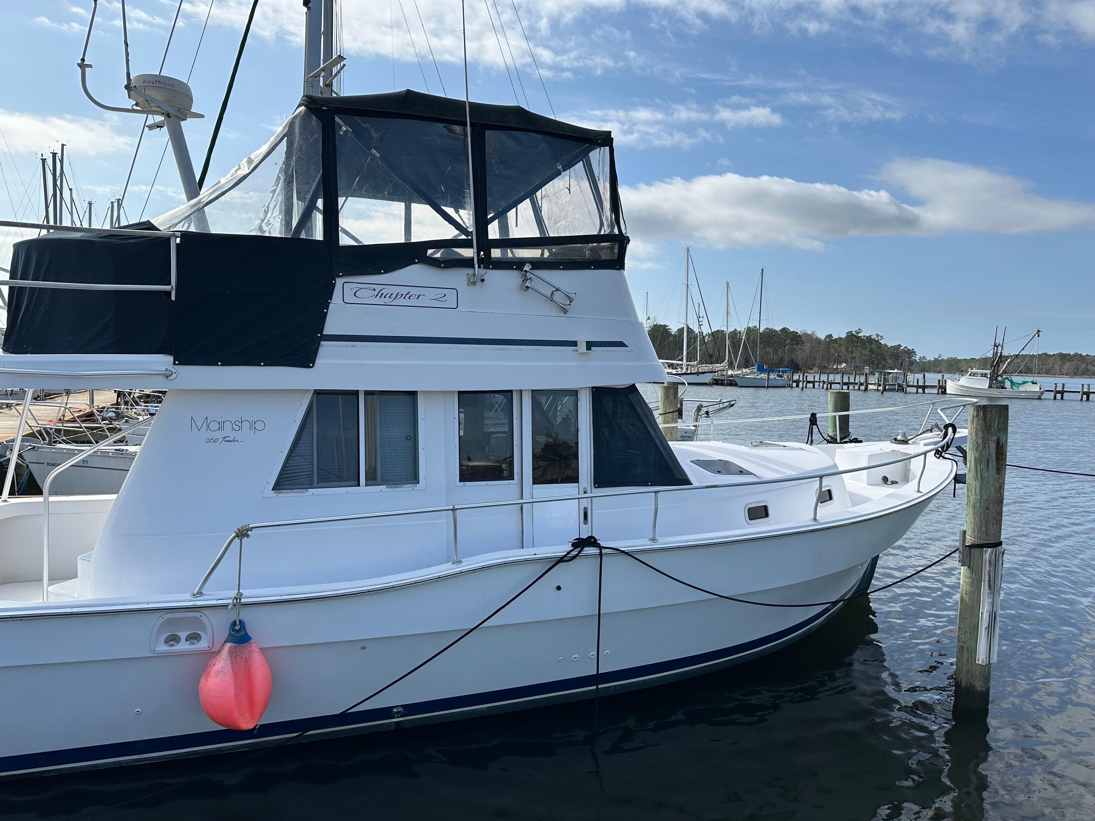 1998 Mainship 350 Trawler docked at marina under blue sky.