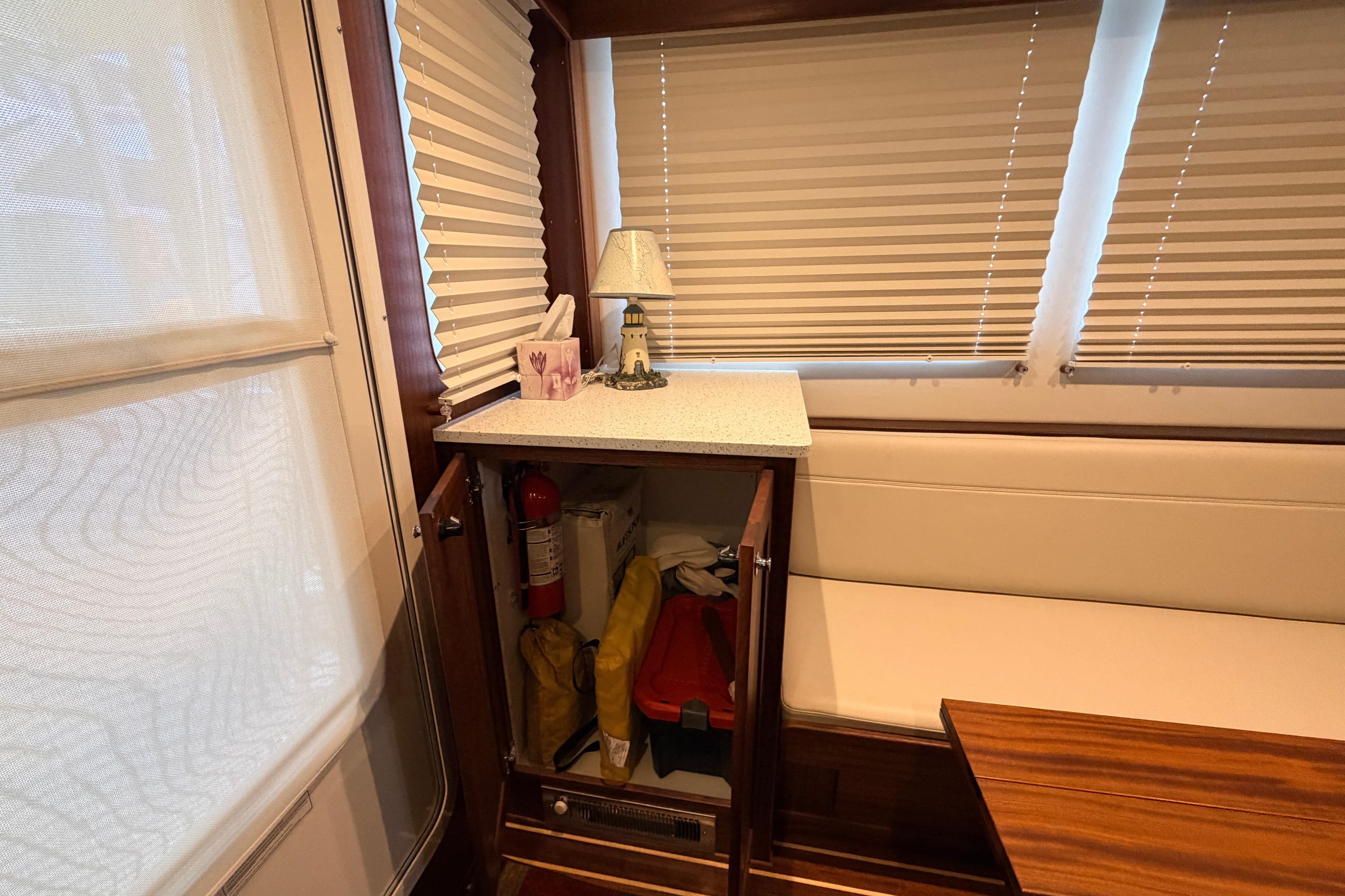 Interior of 2022 American Tug 365 with storage cabinet, fire extinguisher, and nautical decor.