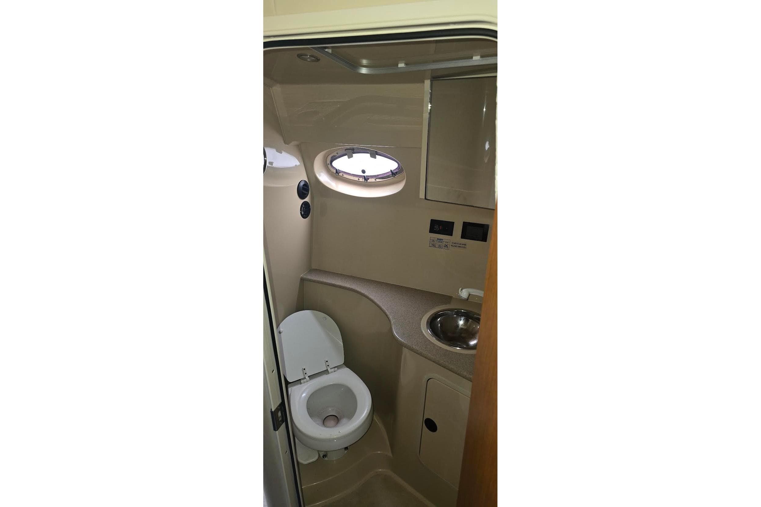 2004 Cruisers 320 Express boat bathroom with toilet, sink, and porthole window.