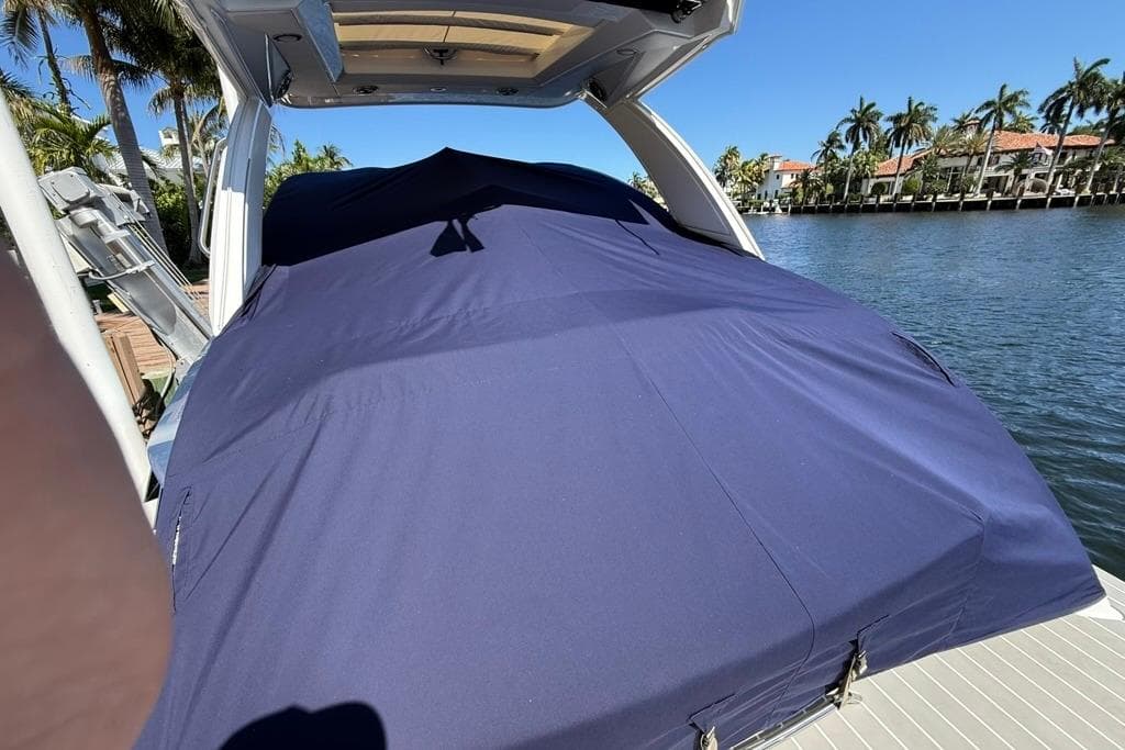 2025 Formula 330 Crossover Bowrider OB covered, docked by palm-lined waterfront.