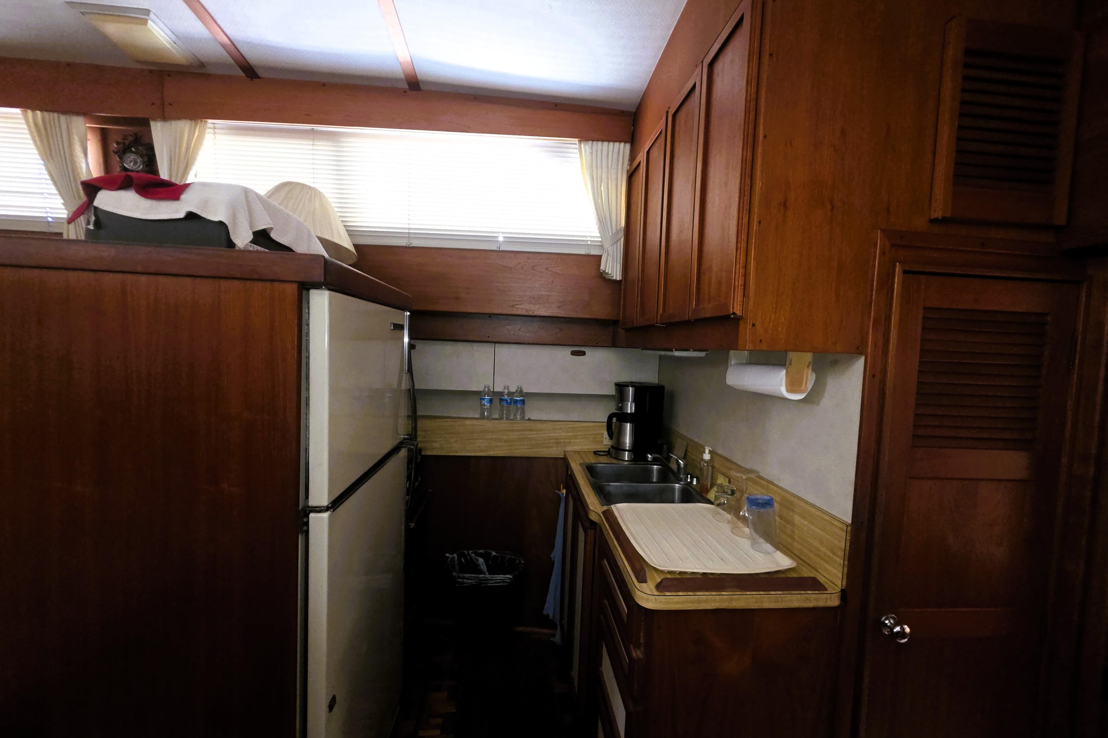 1979 Trojan 44 Motor Yacht kitchen with wood cabinets, sink, and refrigerator.