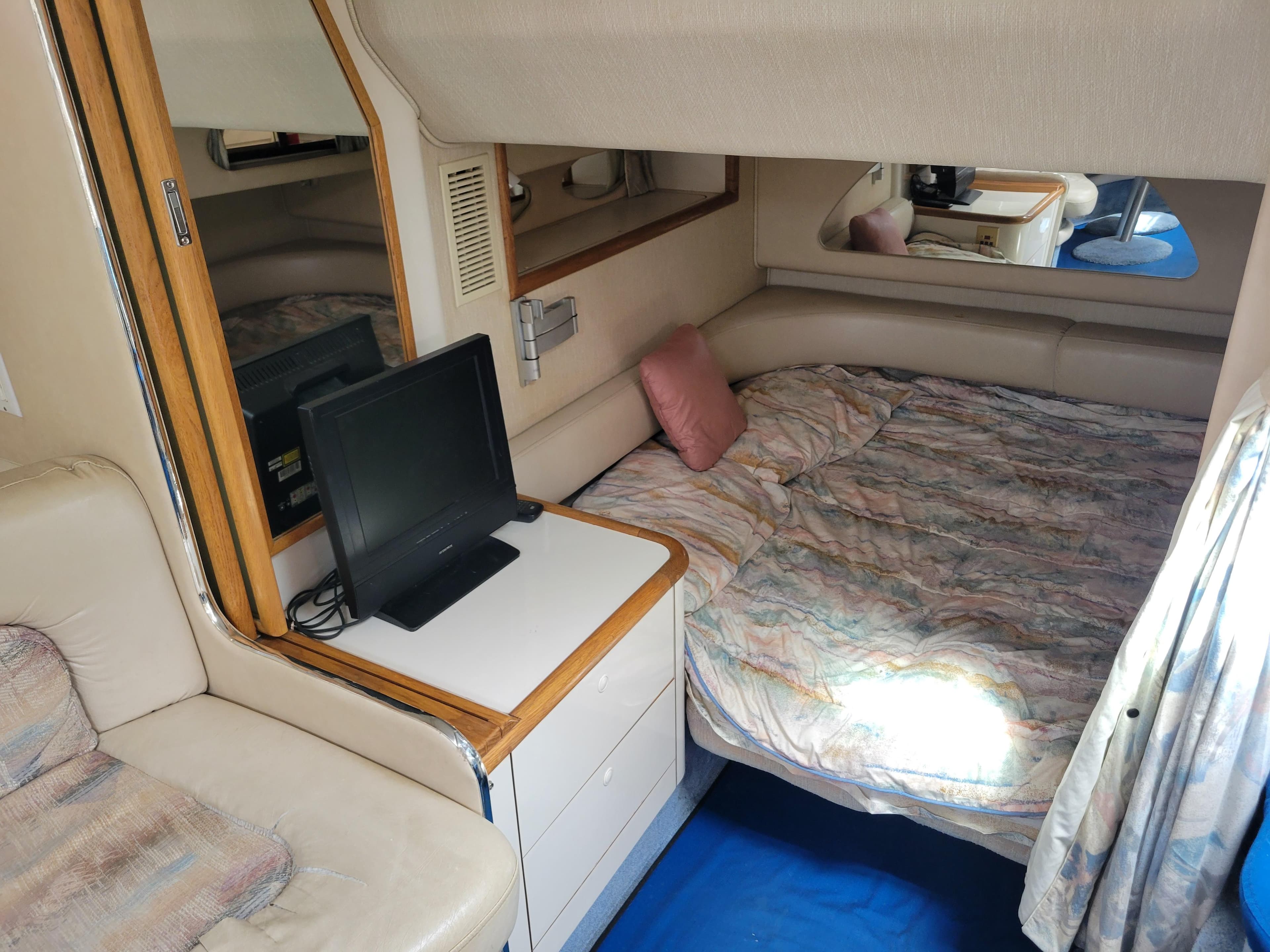1995 Sea Ray 370 Sundancer cabin with bed, TV, and seating area.