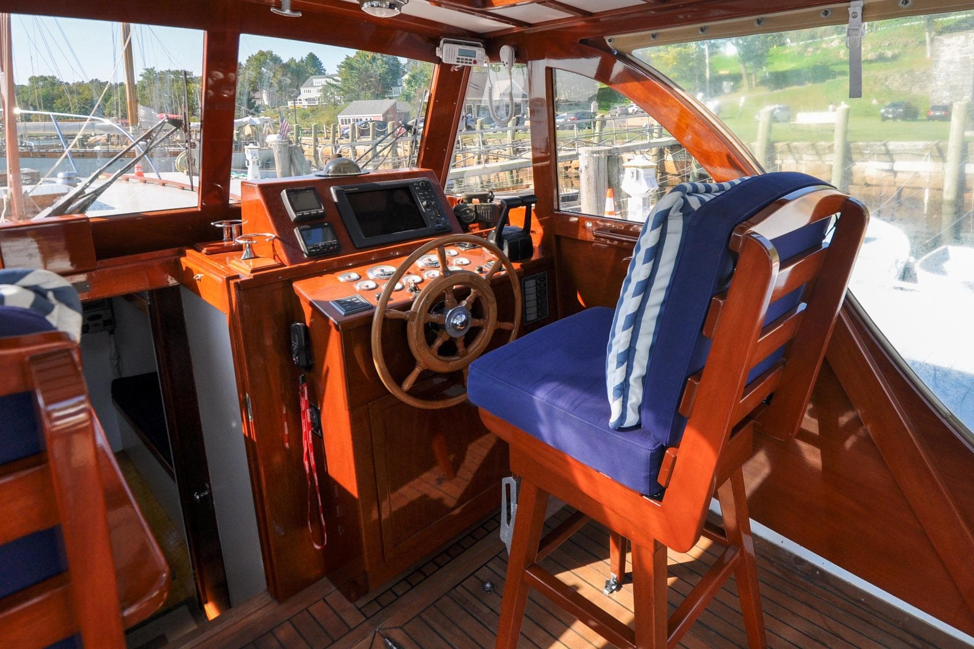 Vintage 1958 Bunker and Ellis 42 boat interior with wooden helm and blue cushioned seat.