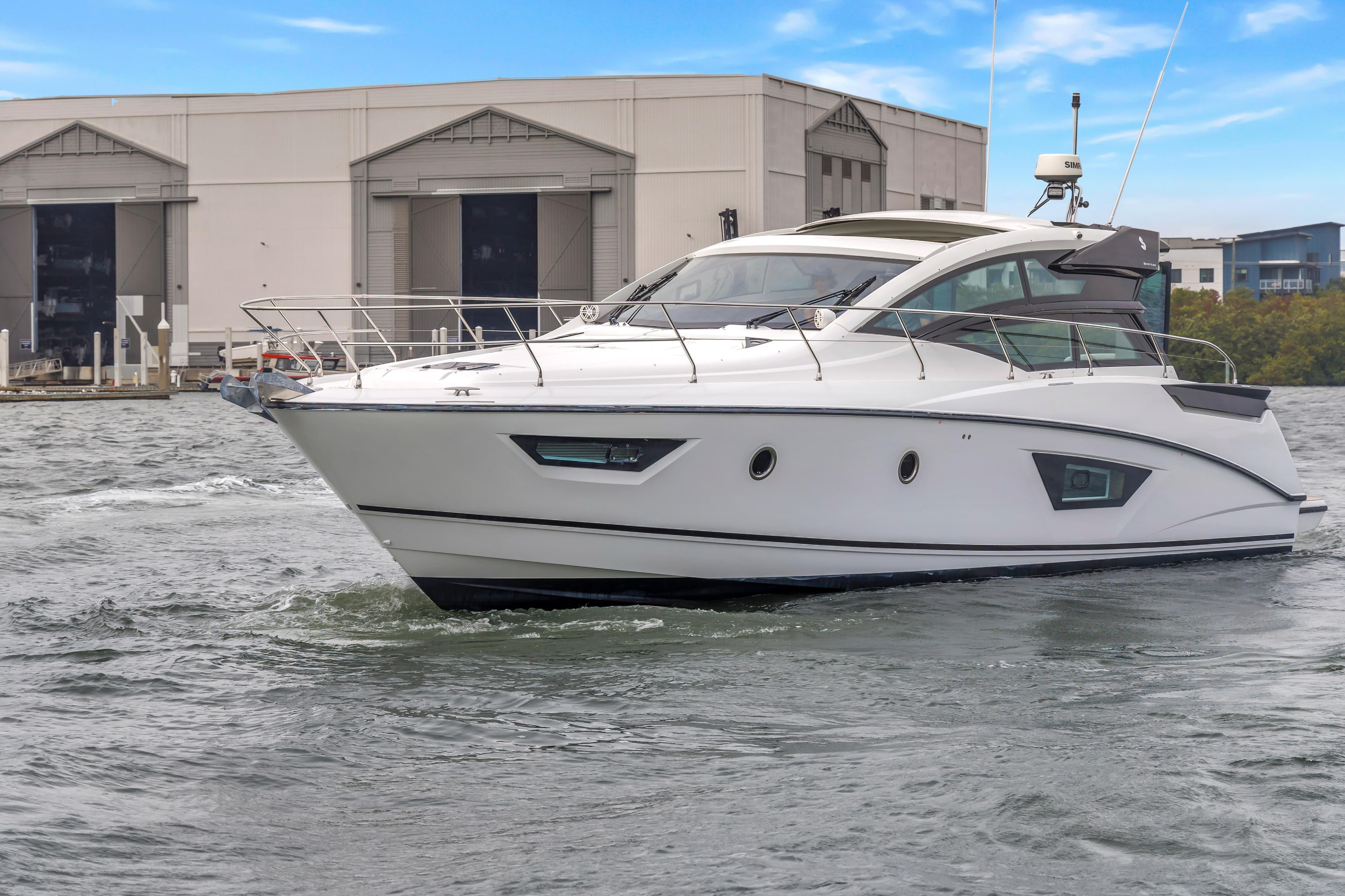2019 Beneteau Gran Turismo 46 yacht cruising near industrial buildings.