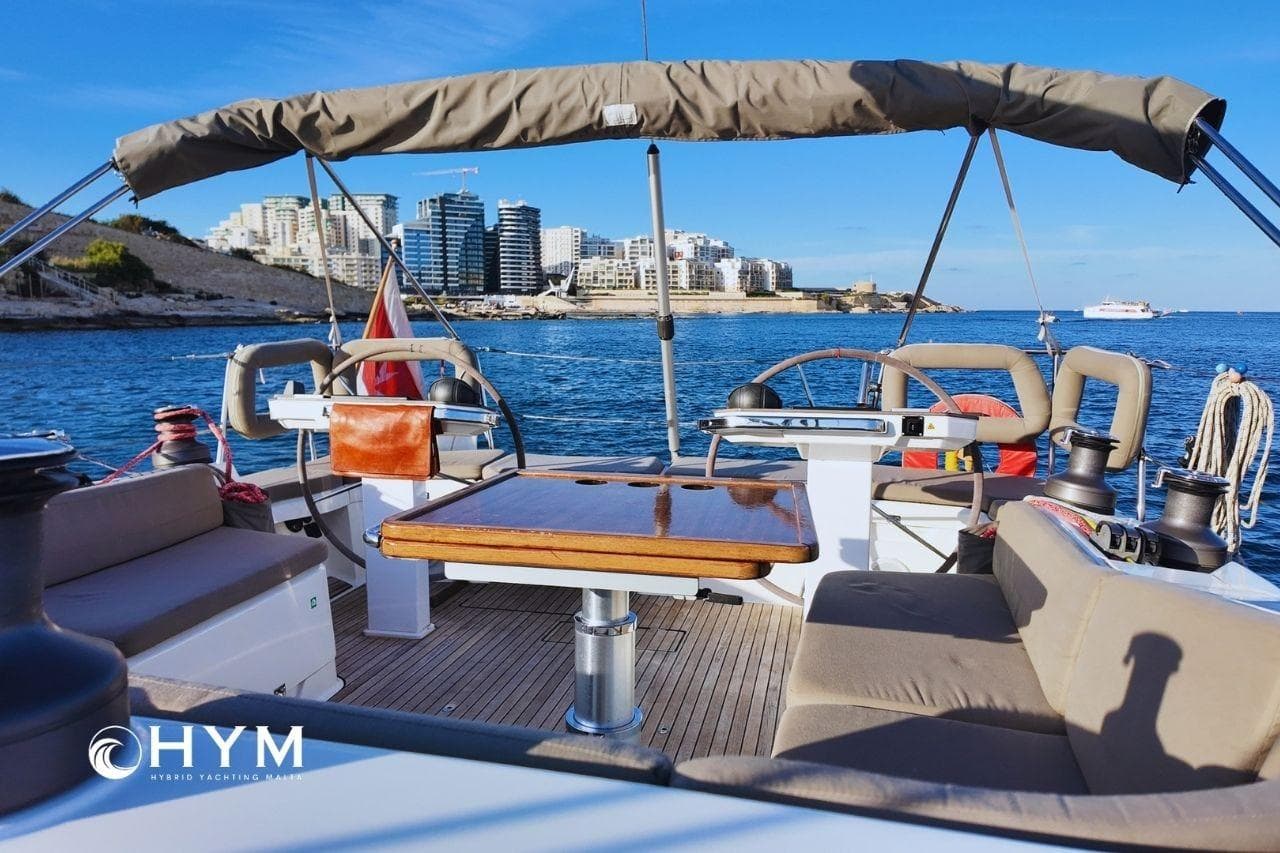 2014 Bavaria Vision 46 yacht interior with cityscape view, featuring comfortable seating and steering wheel.