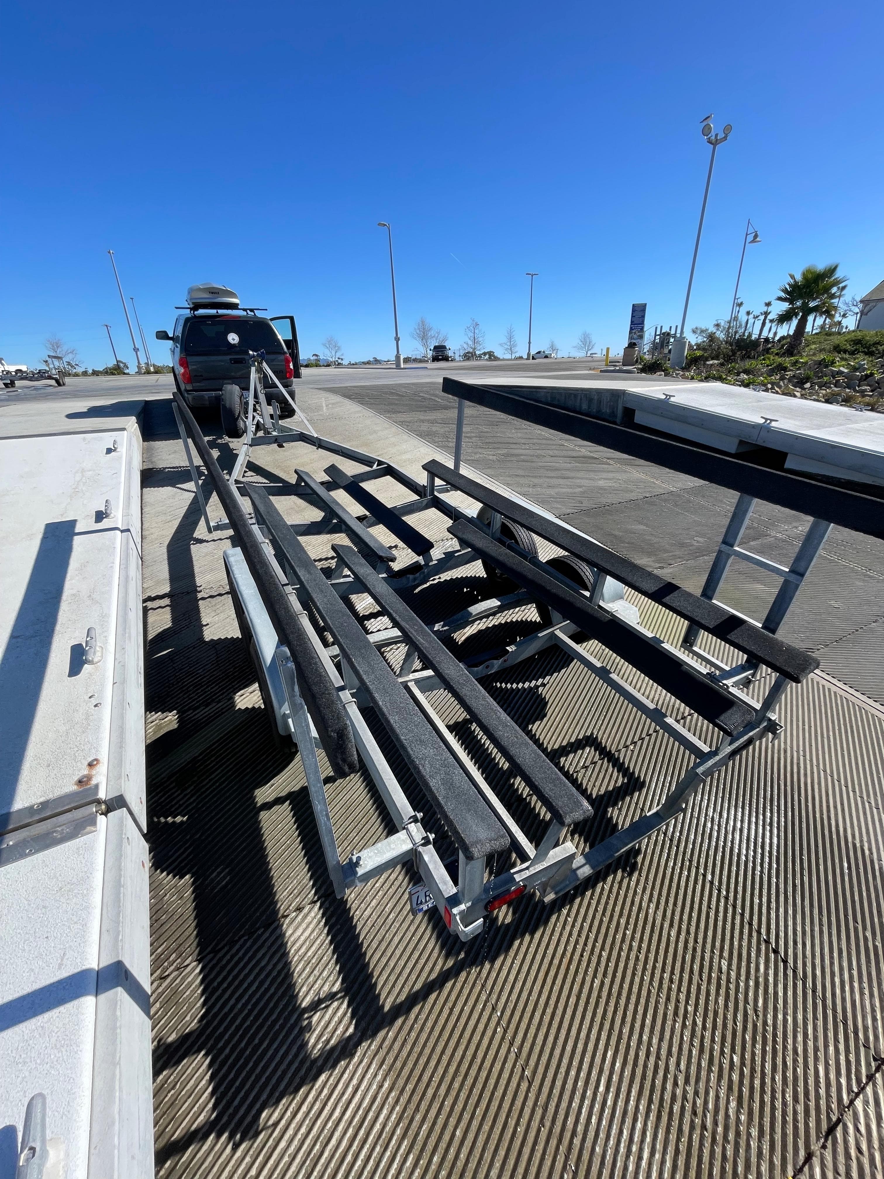Boat trailer for 1984 Farallon 25 Whaleback at a dock under clear blue sky.
