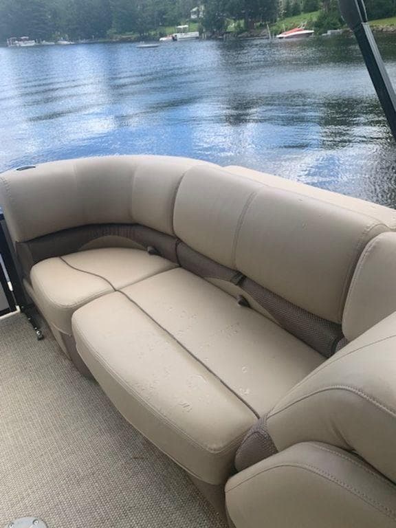 2020 Regency 230 DL3 boat with beige seating by a serene lake.